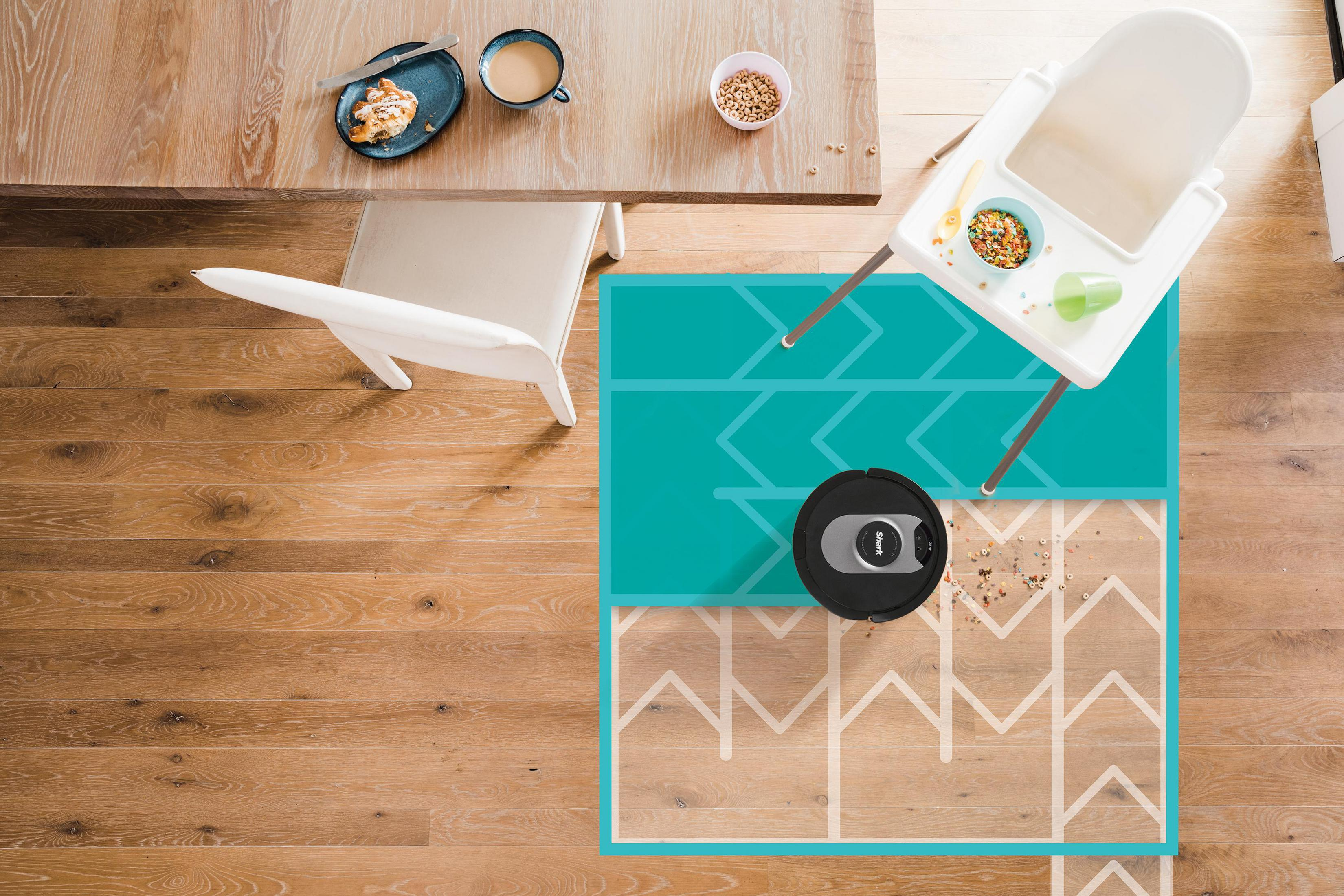 Widok z góry na pokój z drewnianą podłogą, robotem sprzątającym i krzesełkiem do karmienia.