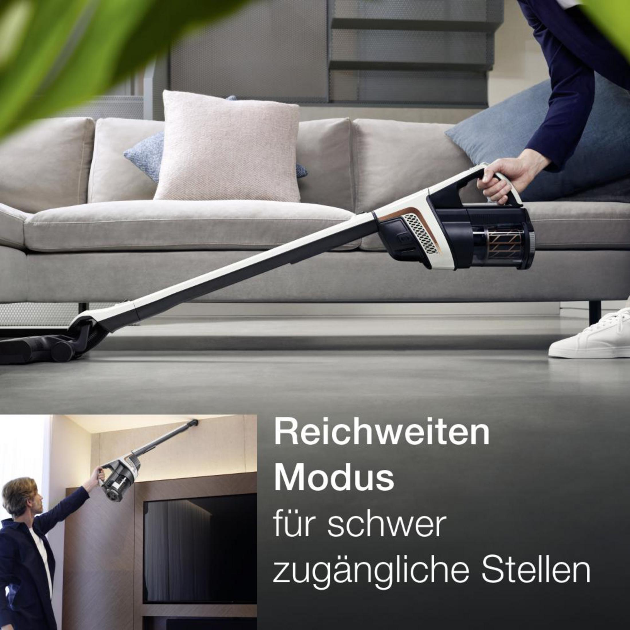 Eine Person saugt den Boden mit einem Staubsauger. Text auf Deutsch: Reichweiten Modus für schwer zugängliche Stellen.