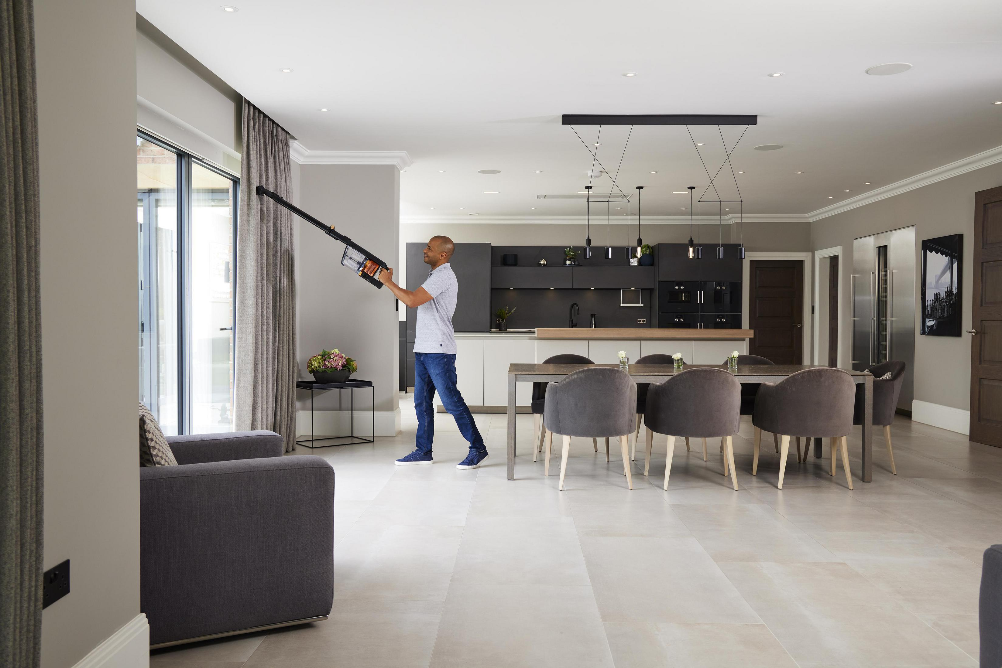 Un hombre aspirando una sala de estar con un diseño interior moderno, luminoso y espacioso.