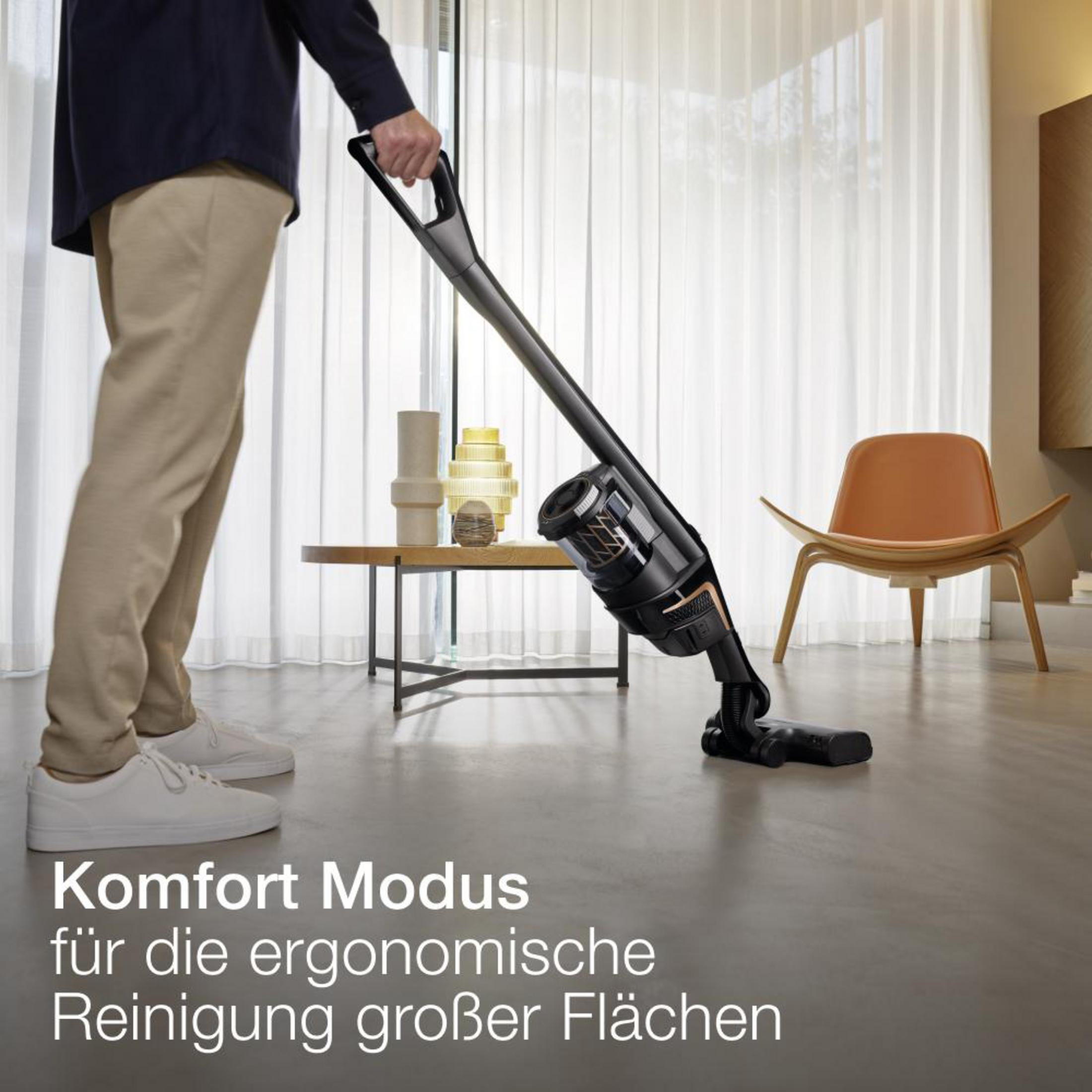 Mann, der mit einem schwarz-grauen Staubsauger den Boden saugt. Text: Komfort Modus für die ergonomische Reinigung.
