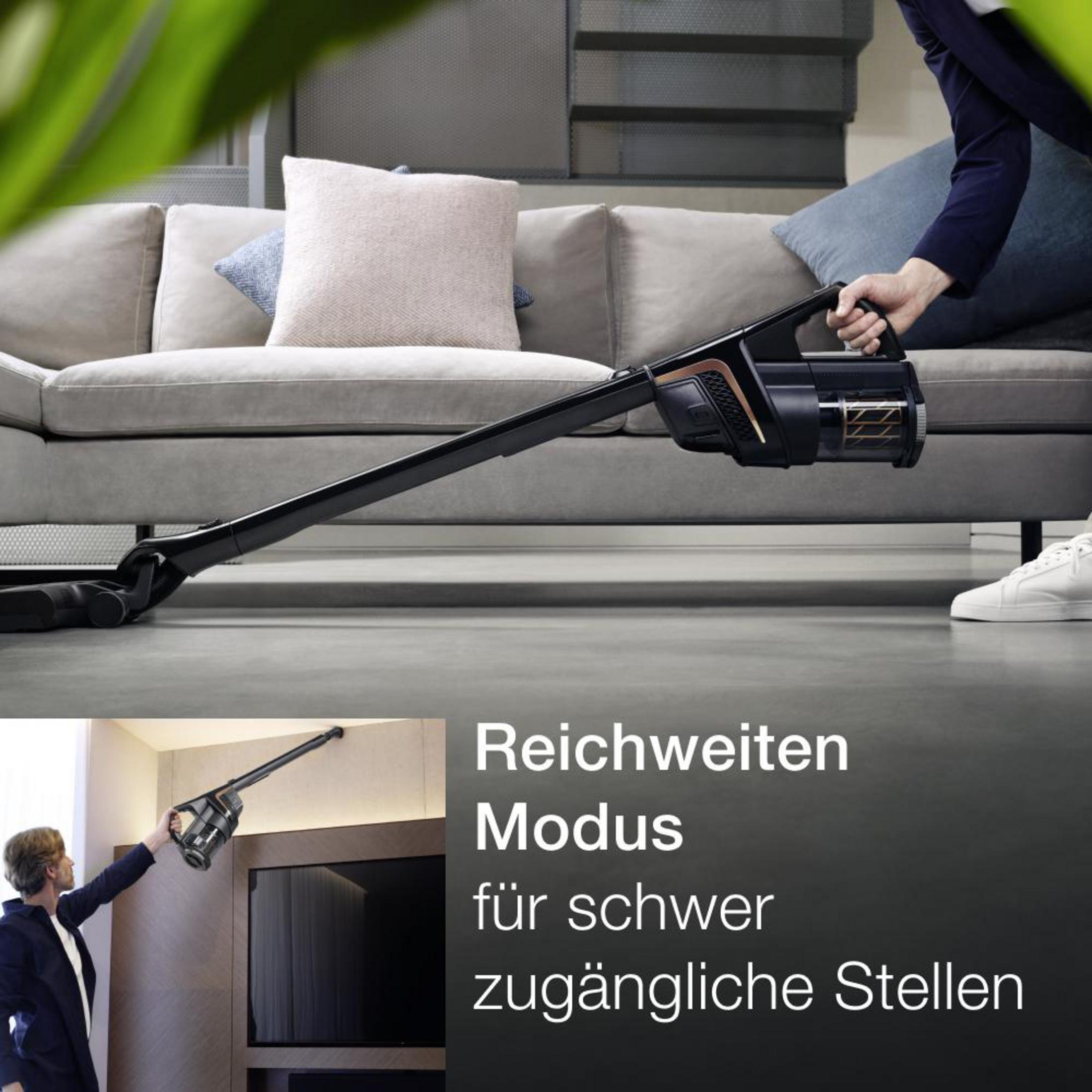 Person, die einen schwarzen Stielstaubsauger auf dem Boden benutzt. Text auf Deutsch.