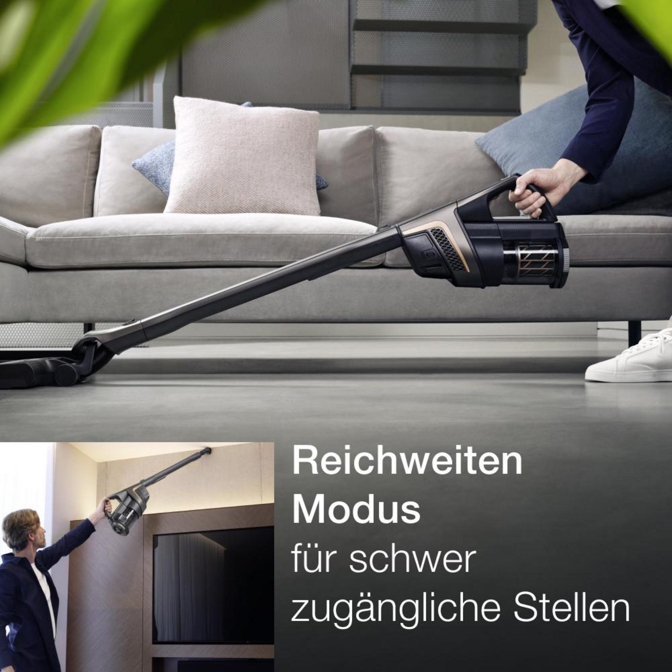 Eine Person benutzt einen Staubsauger. Text lautet: Reichweitenmodus für schwer zugängliche Stellen.