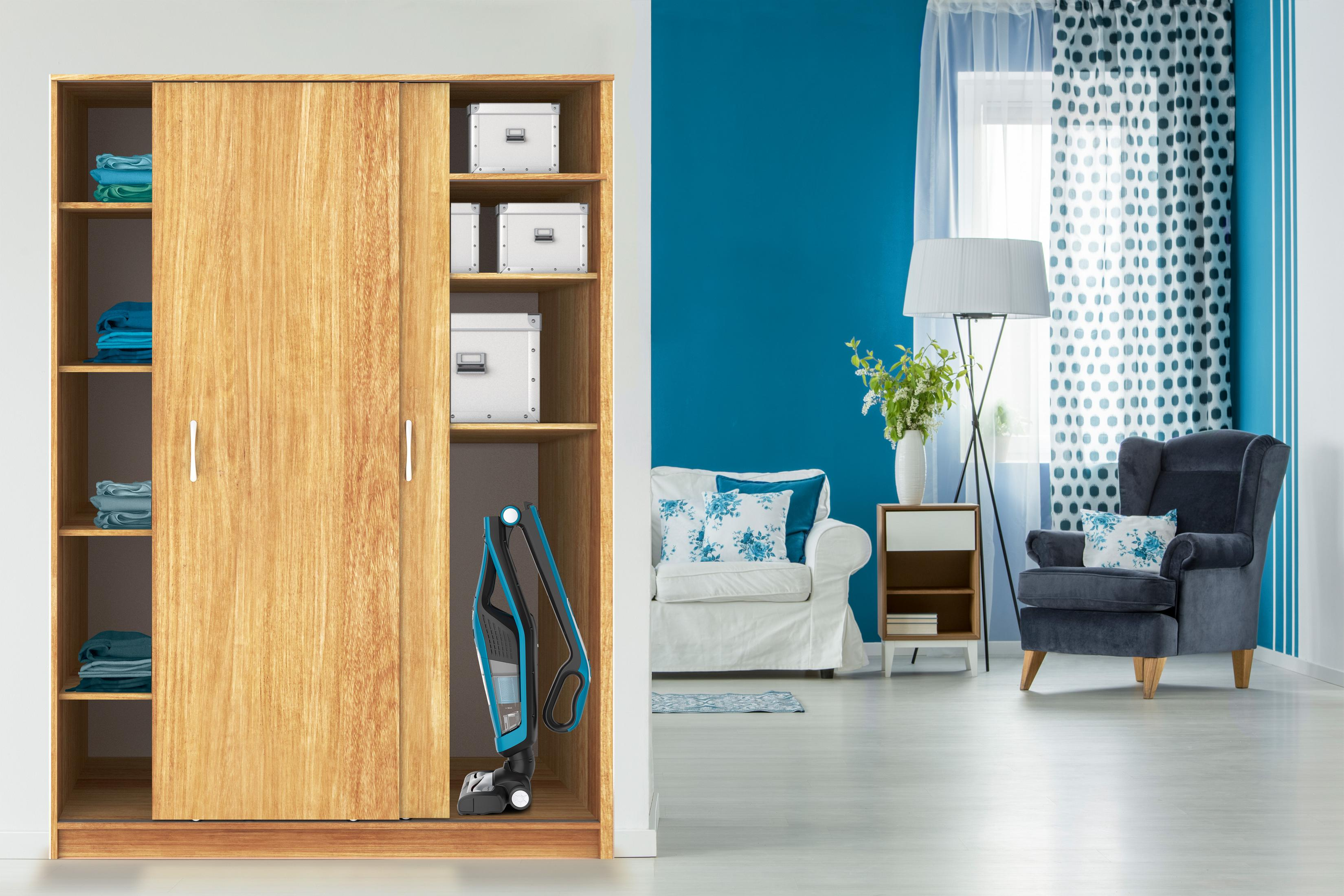 Armario de madera con puertas correderas, abierto para revelar una aspiradora y una sala de estar.