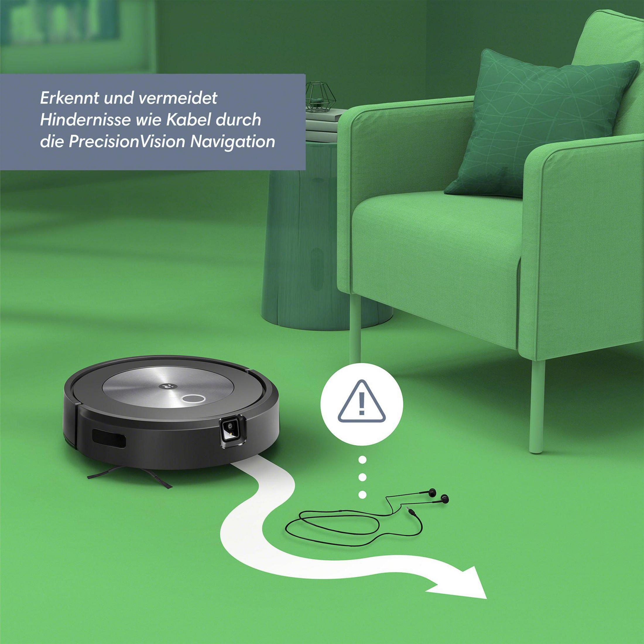 Ein schwarzer Roboter-Staubsauger navigiert über einen grünen Boden und vermeidet ein Kabel mit Warnschild.