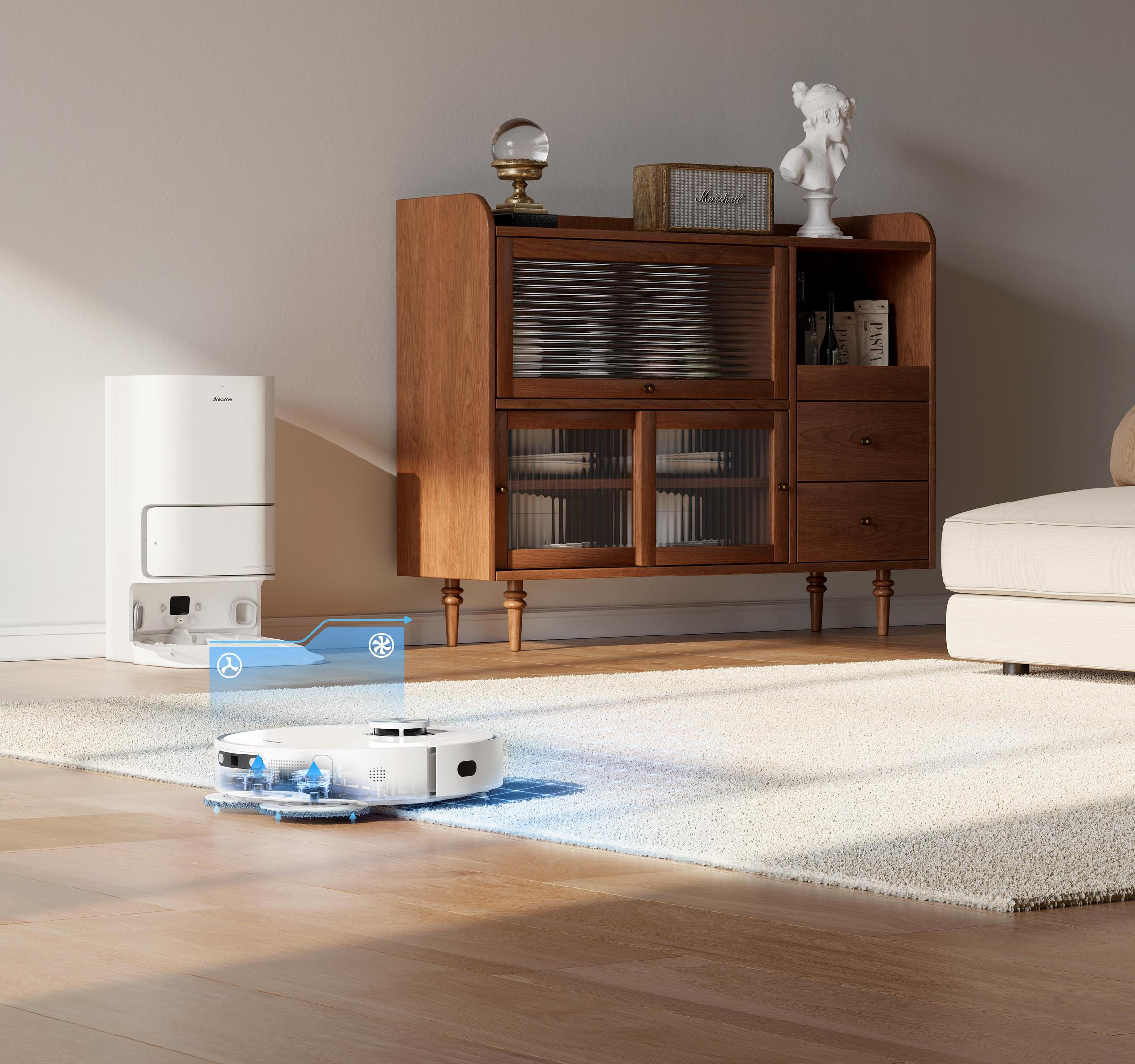 Robot odkurzający i stacja ładująca w pokoju z meblami i dywanem. Podłoga jest drewniana.