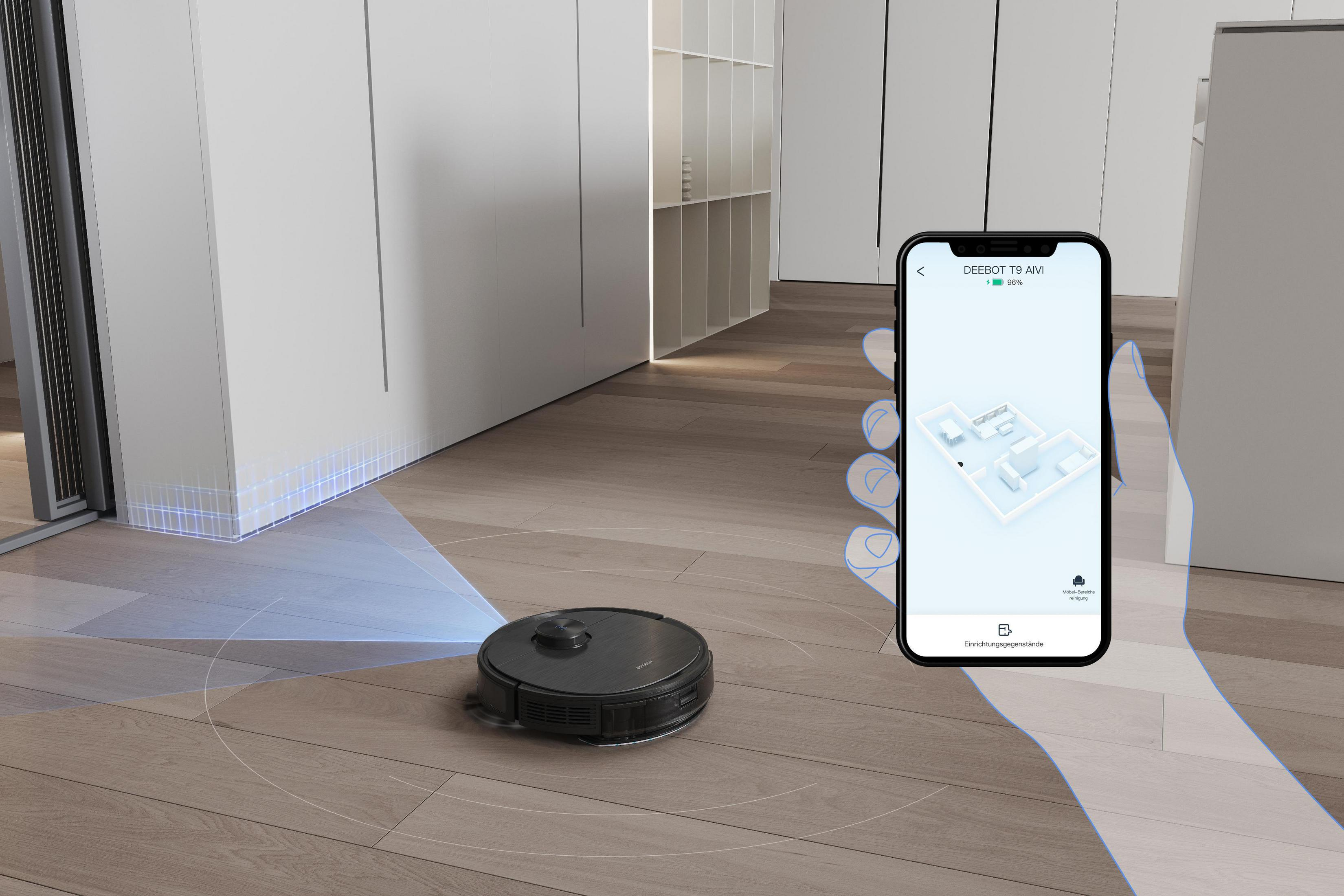 Ein Roboter-Staubsauger wird über ein Smartphone gesteuert. Der Boden ist aus Holz. Der Raum hat weiße Wände.