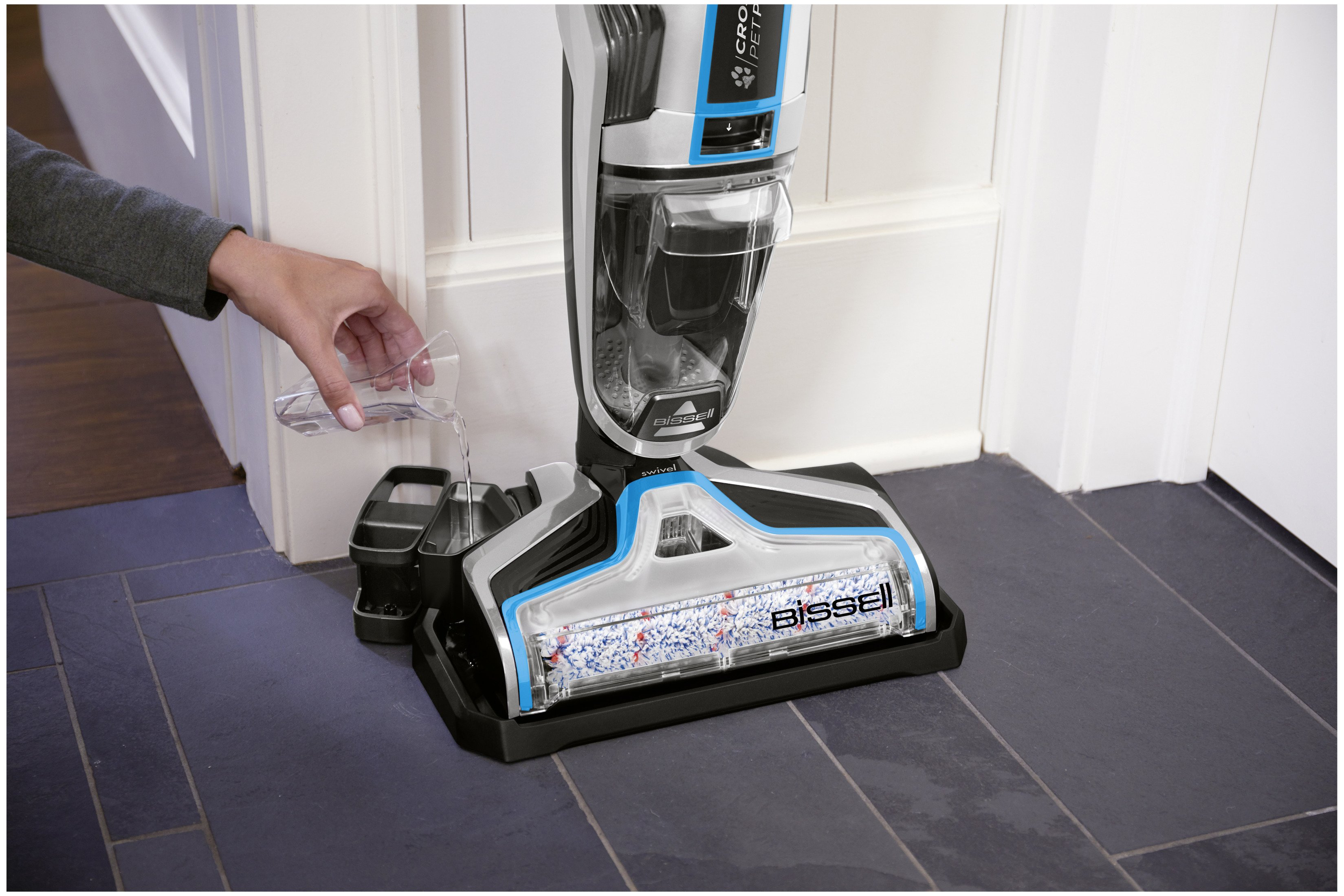 Osoba wlewa wodę do odkurzacza Bissell CrossWave na kafelkowej podłodze.