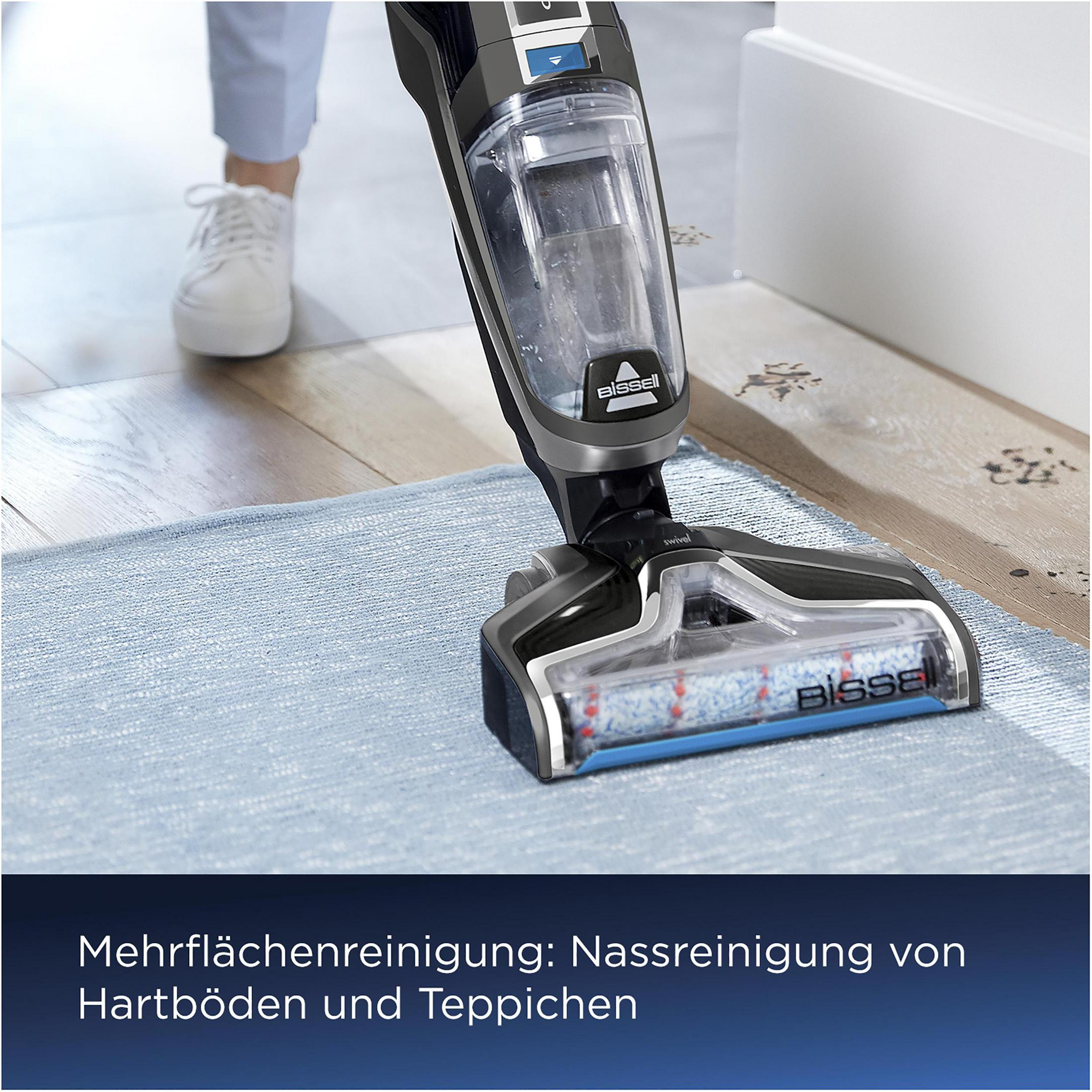 Un nettoyeur de sol Bissell nettoyant un tapis bleu sur un sol en bois.