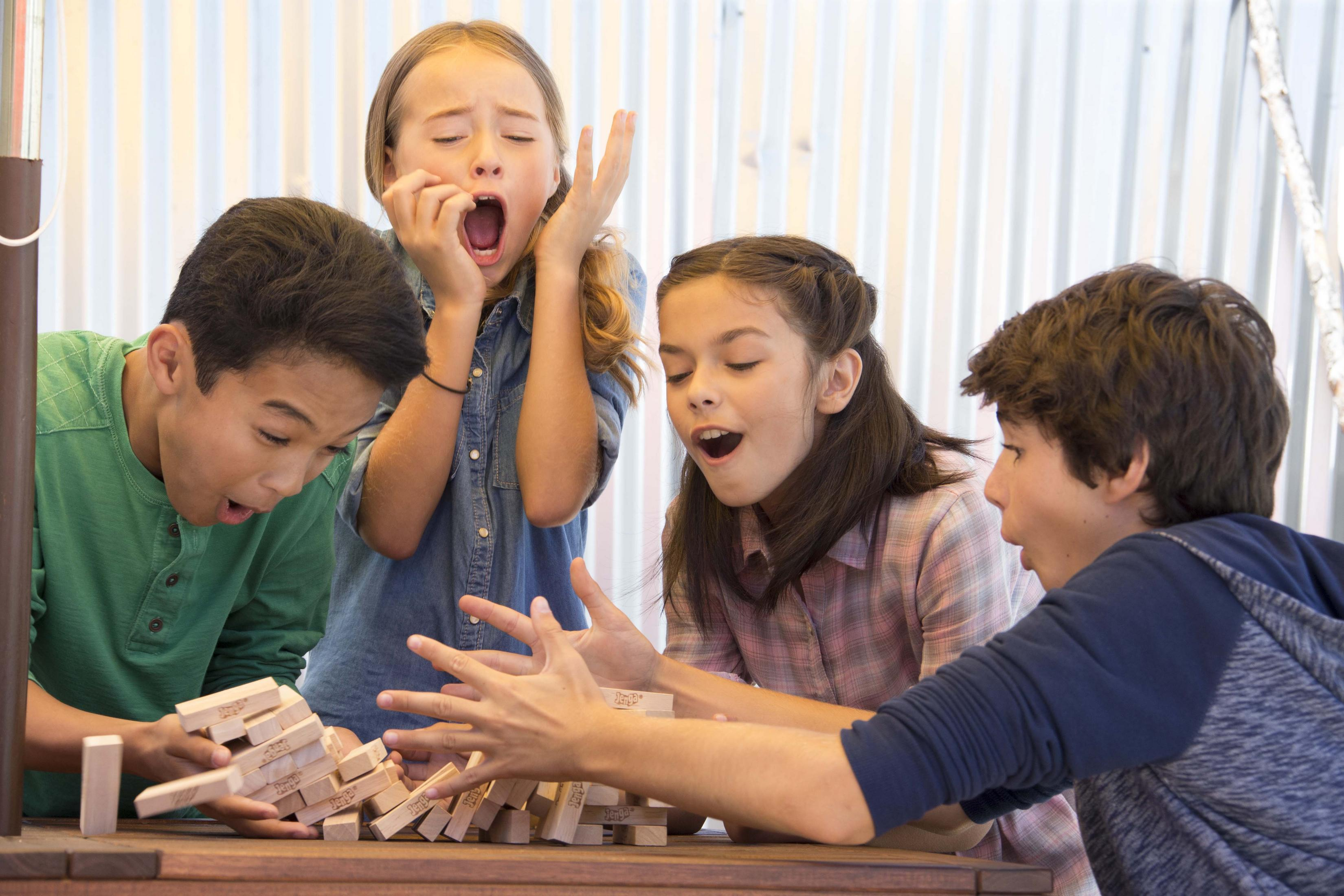 Czterech dzieci gra w Jengę. Jedno zaraz przewróci wieżę, inni wzdychają.