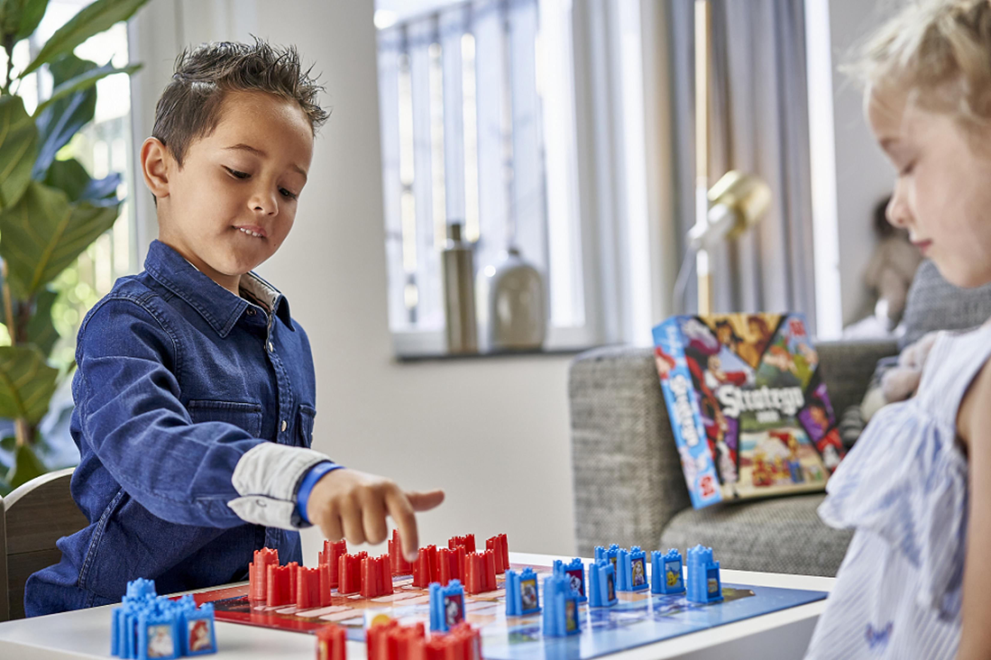 Un niño y una niña jugando al juego Disney Stratego Junior.