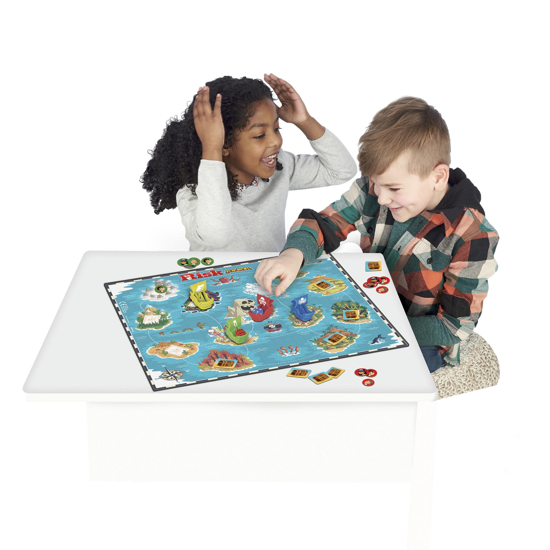Zwei Kinder spielen ein Brettspiel auf einem weißen Tisch. Das Spiel ist eine Karte.