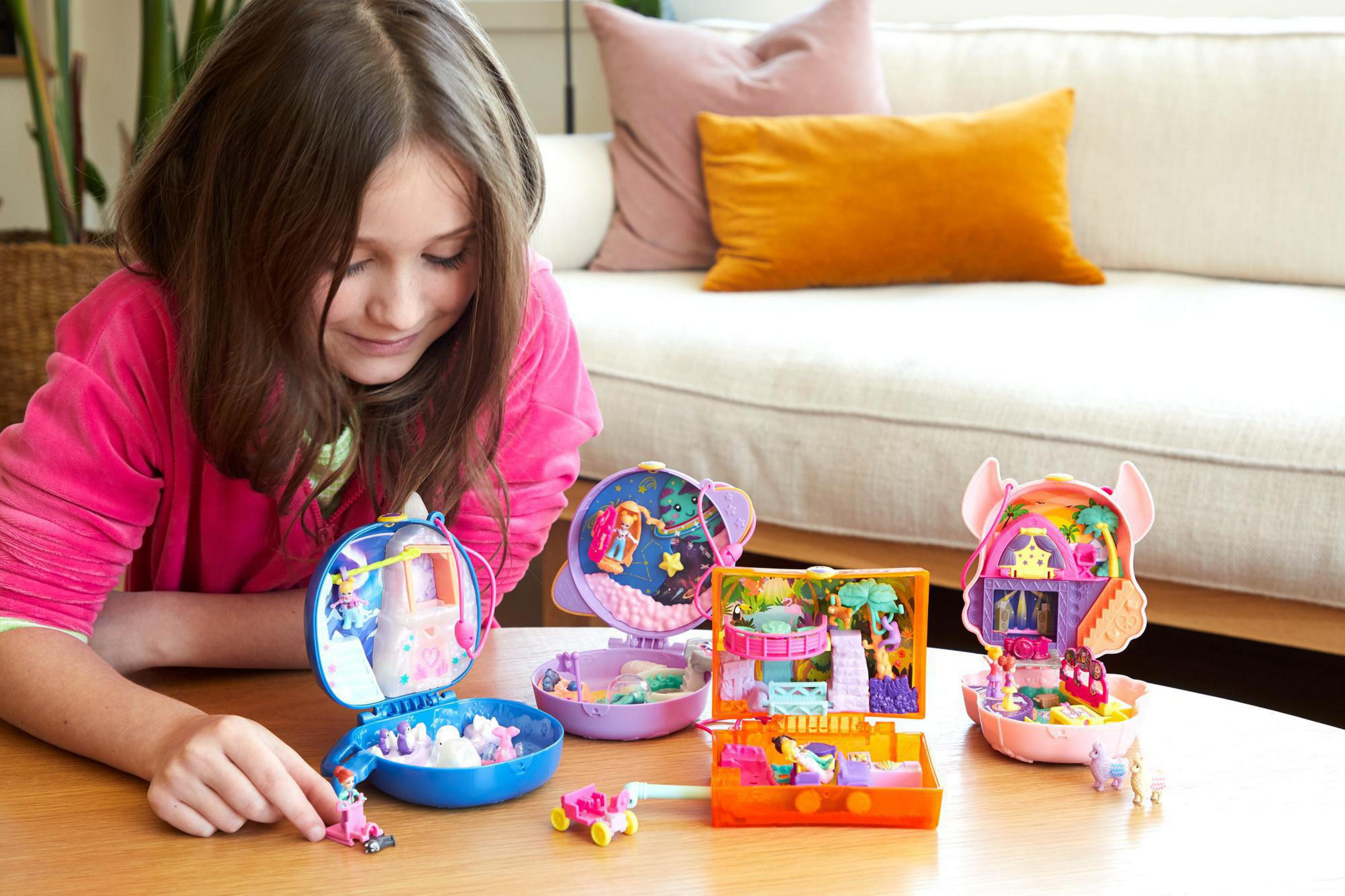 Una niña juega con juguetes Polly Pocket sobre una mesa.