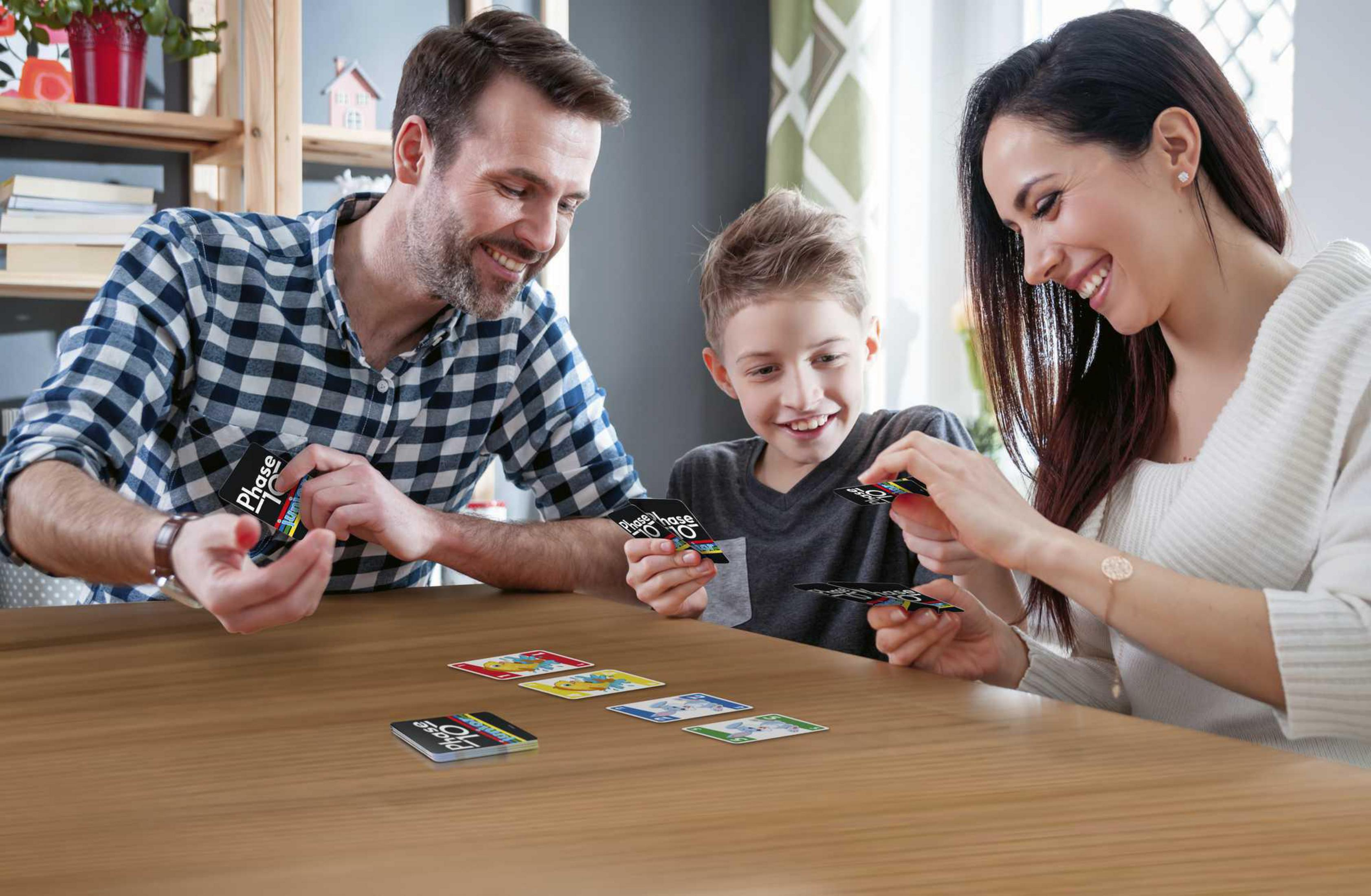 Famiglia che gioca a carte, Phase 10. Sorridono e guardano le carte.
