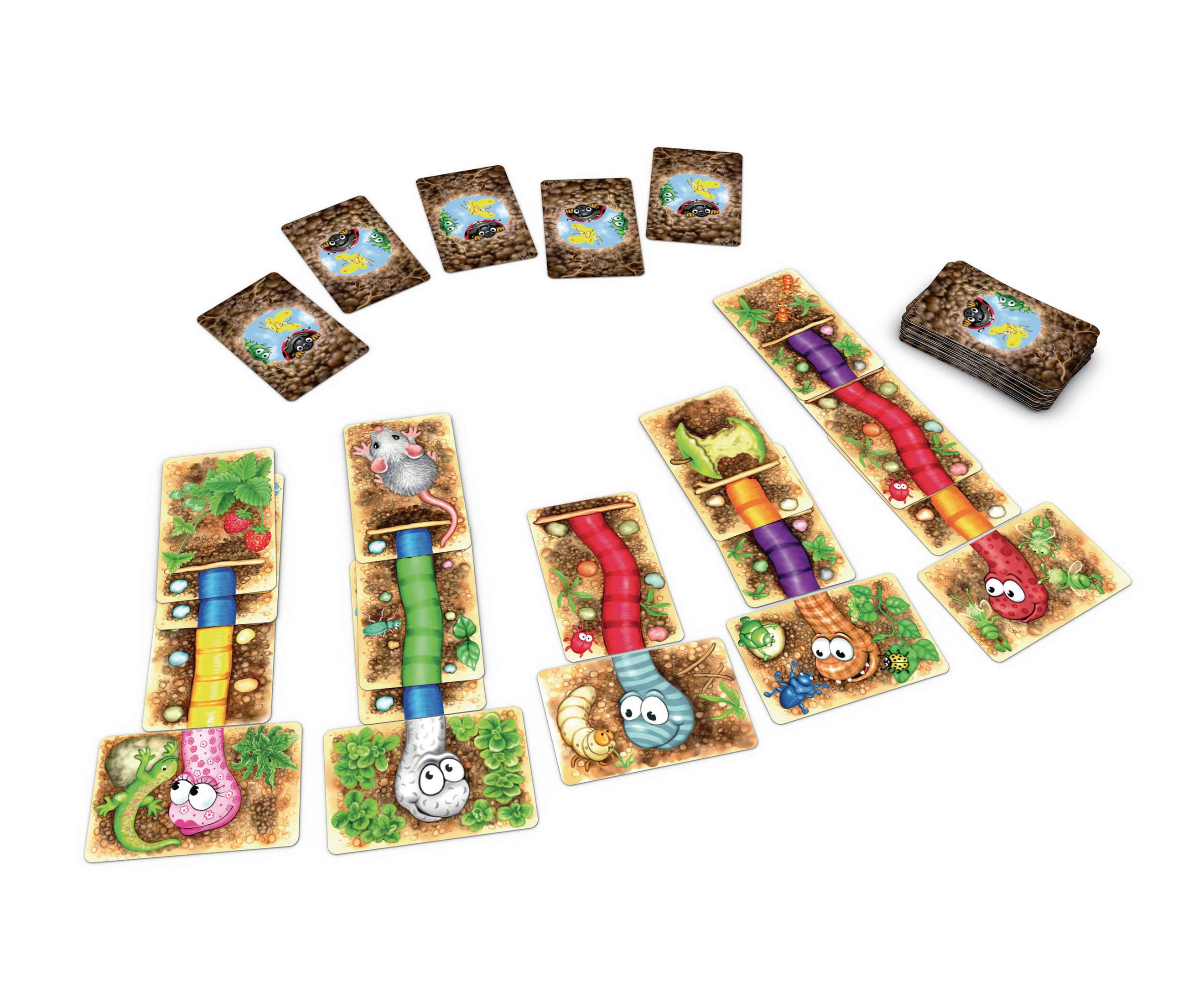 Ein Brettspiel-Setup mit bunten Karten, die Tunnel und Kreaturen zeigen, auf einer weißen Oberfläche angeordnet.