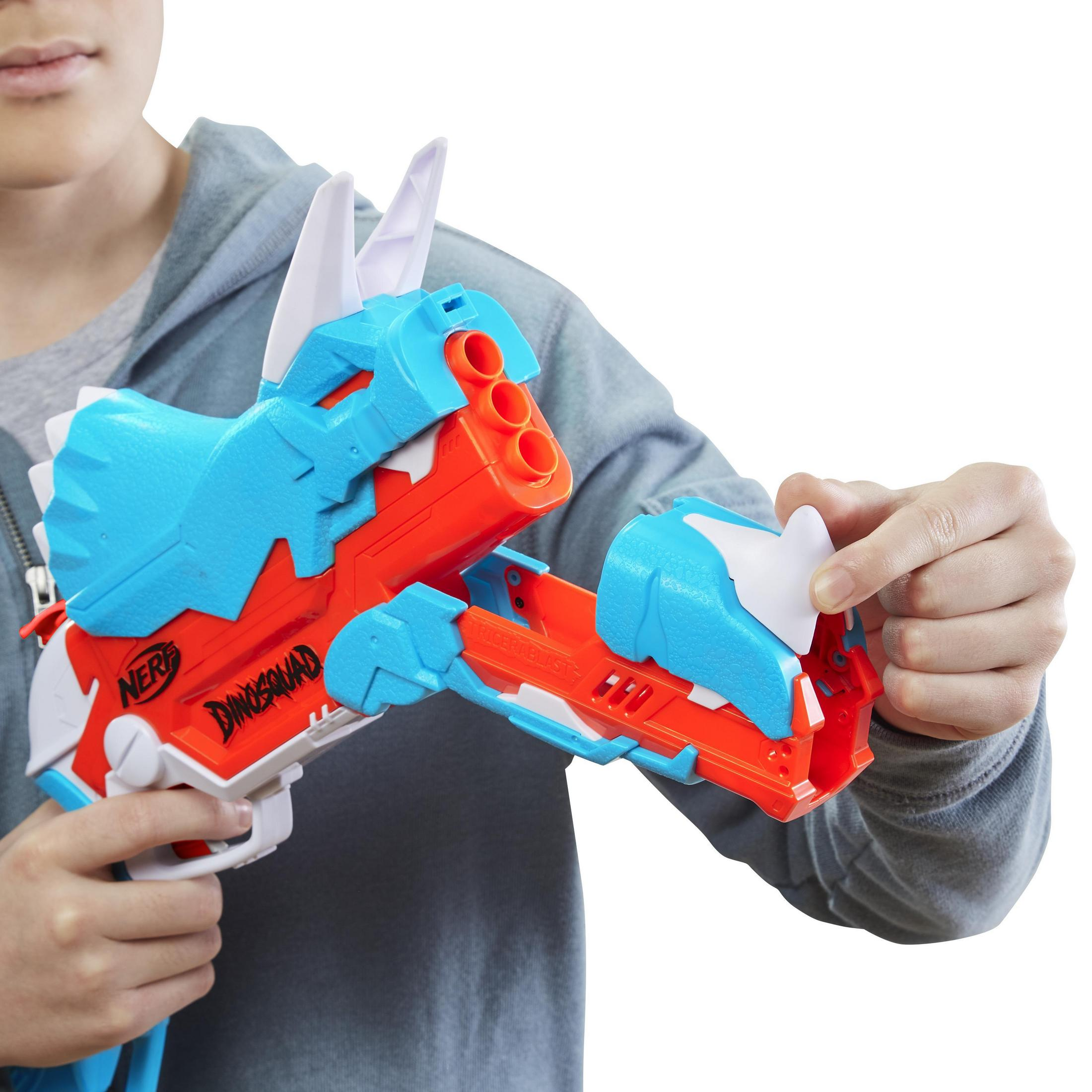 Un niño sostiene una pistola de juguete azul y naranja, una pistola Nerf DinoSquad.