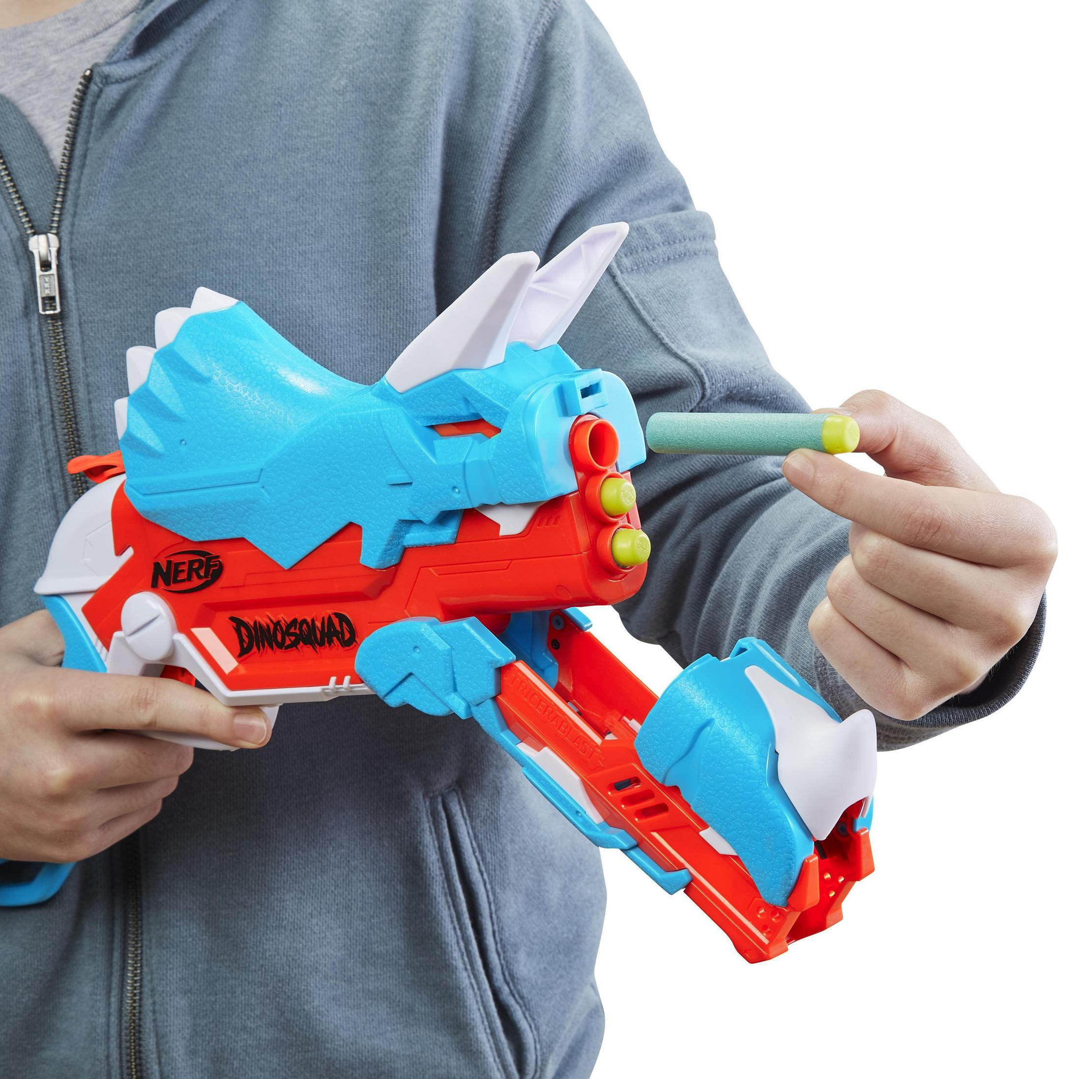Una persona sosteniendo una pistola Nerf azul, roja y blanca. El arma parece un dinosaurio.