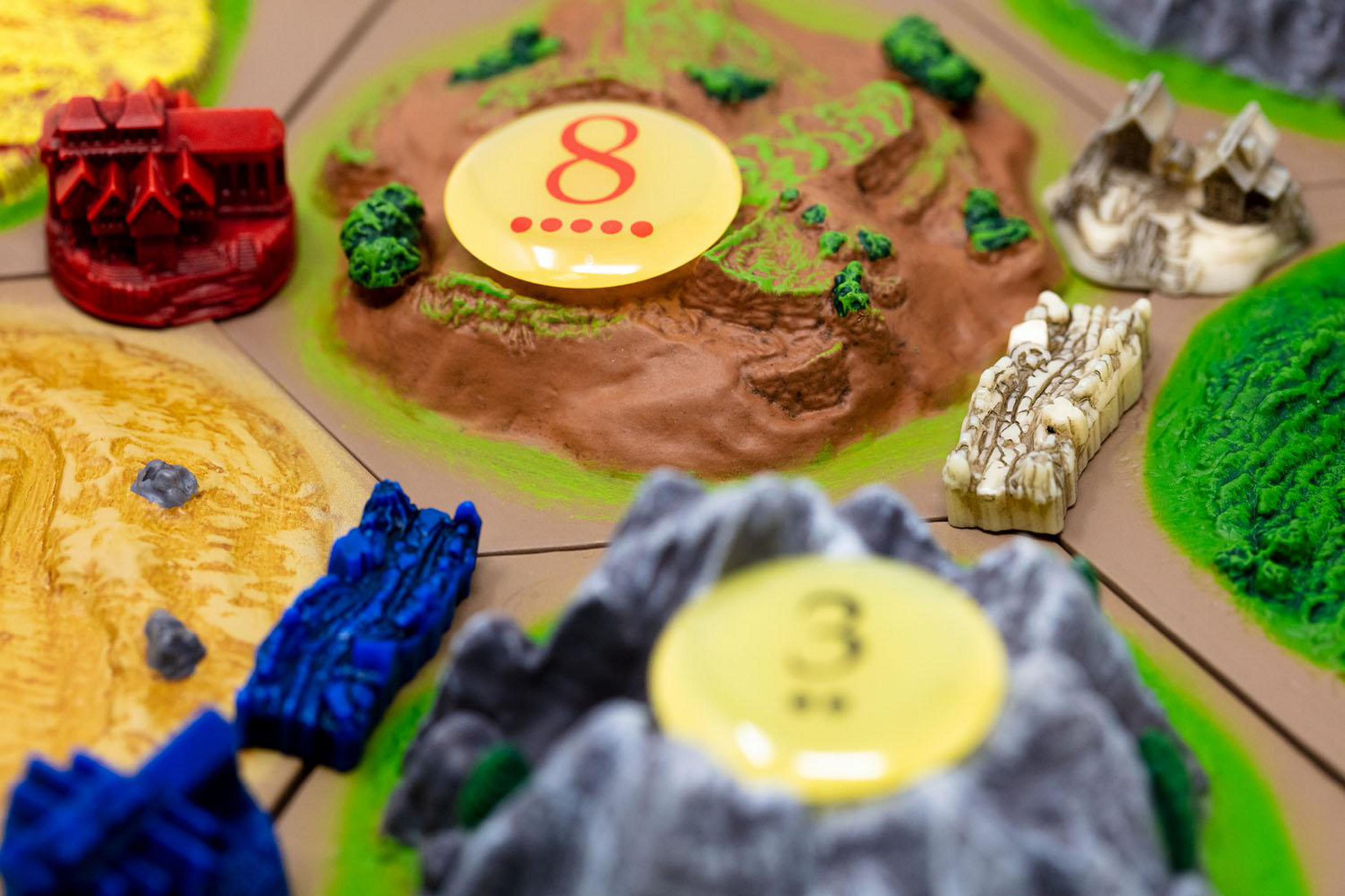 Zbliżenie gry planszowej z elementami terenu i ponumerowanymi żetonami.