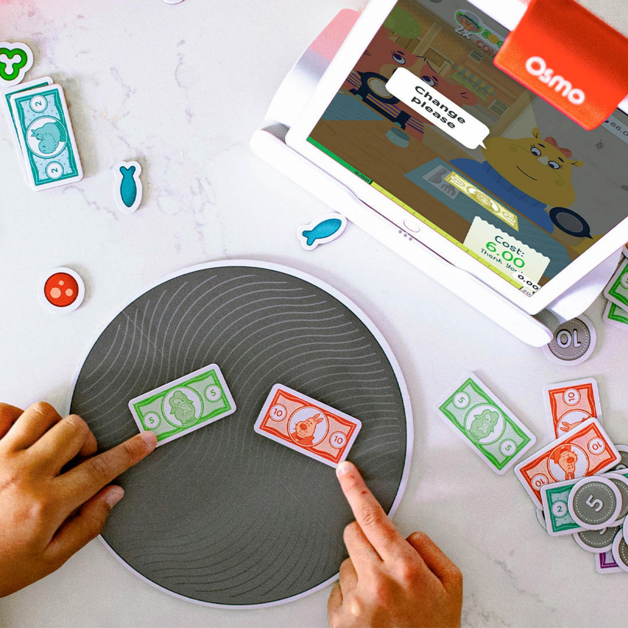Ein Kind spielt ein Spiel auf einem Tablet mit Geldscheinen. Ein Display zeigt Text.