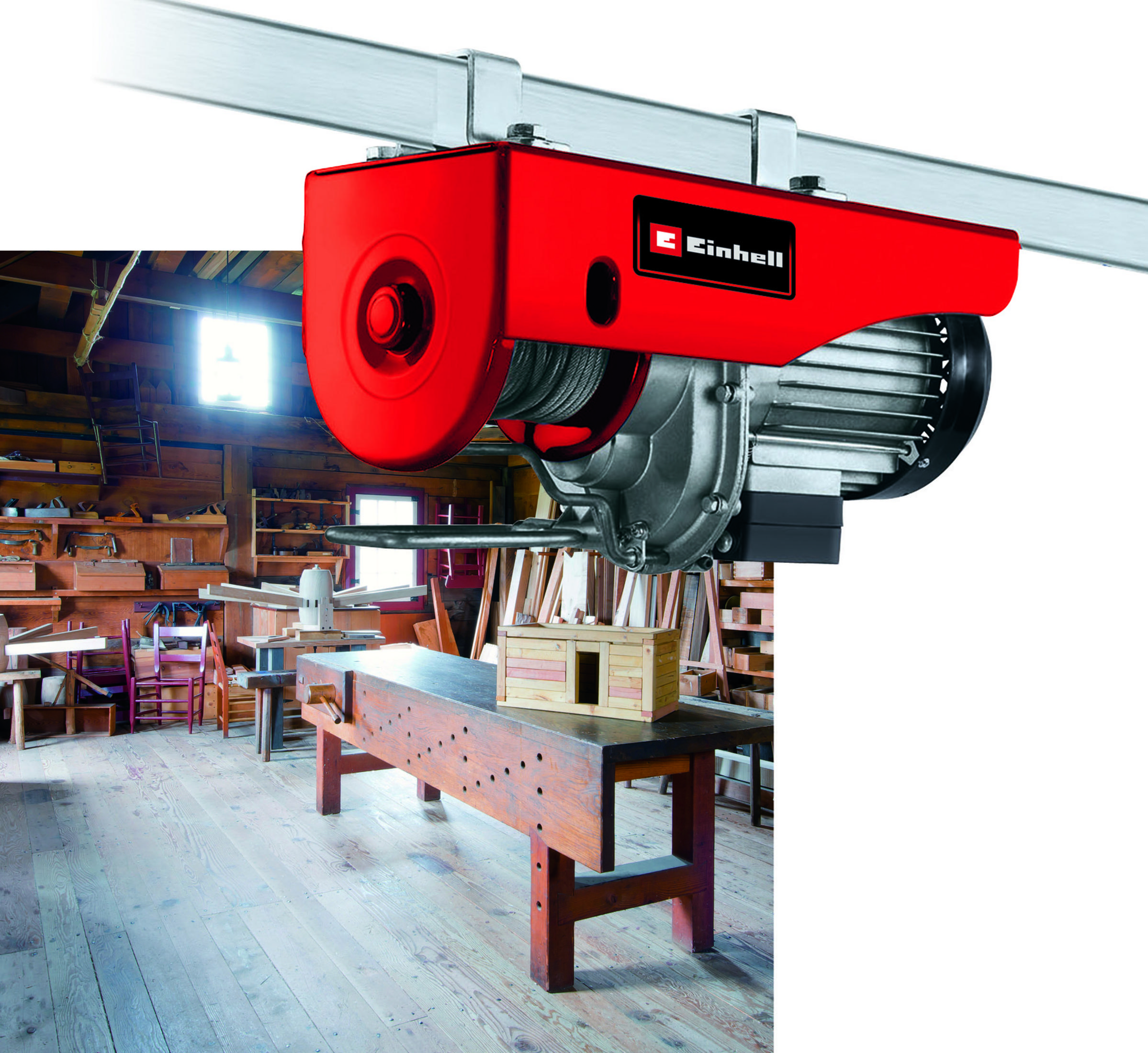 Roter Elektro-Hebezug an einem Träger in einer Werkstatt mit Werkzeugen und Holzobjekten.