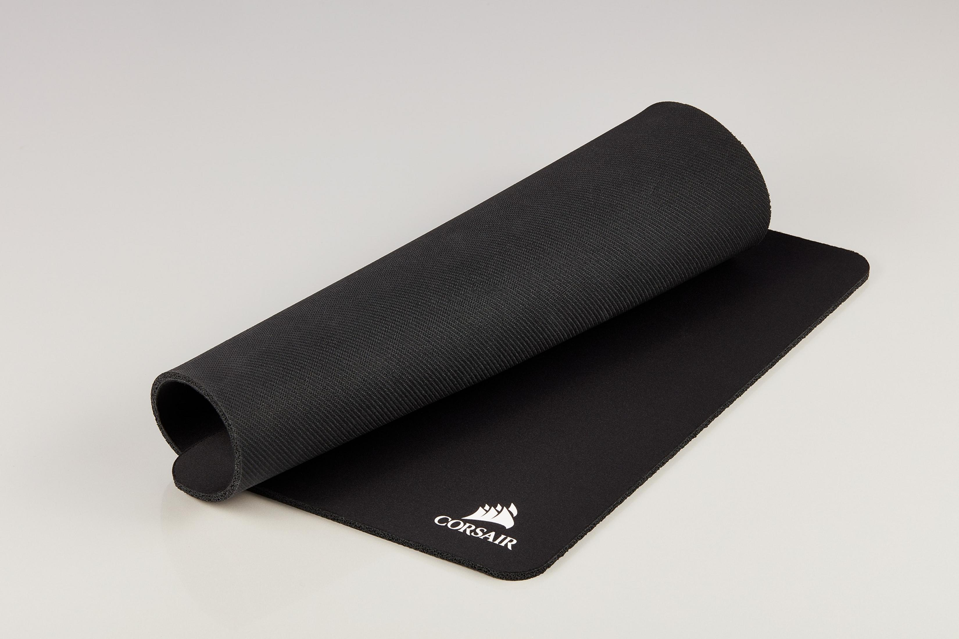 Czarna podkładka pod mysz Corsair, częściowo zwinięta, na białej powierzchni. Logo Corsair widoczne.