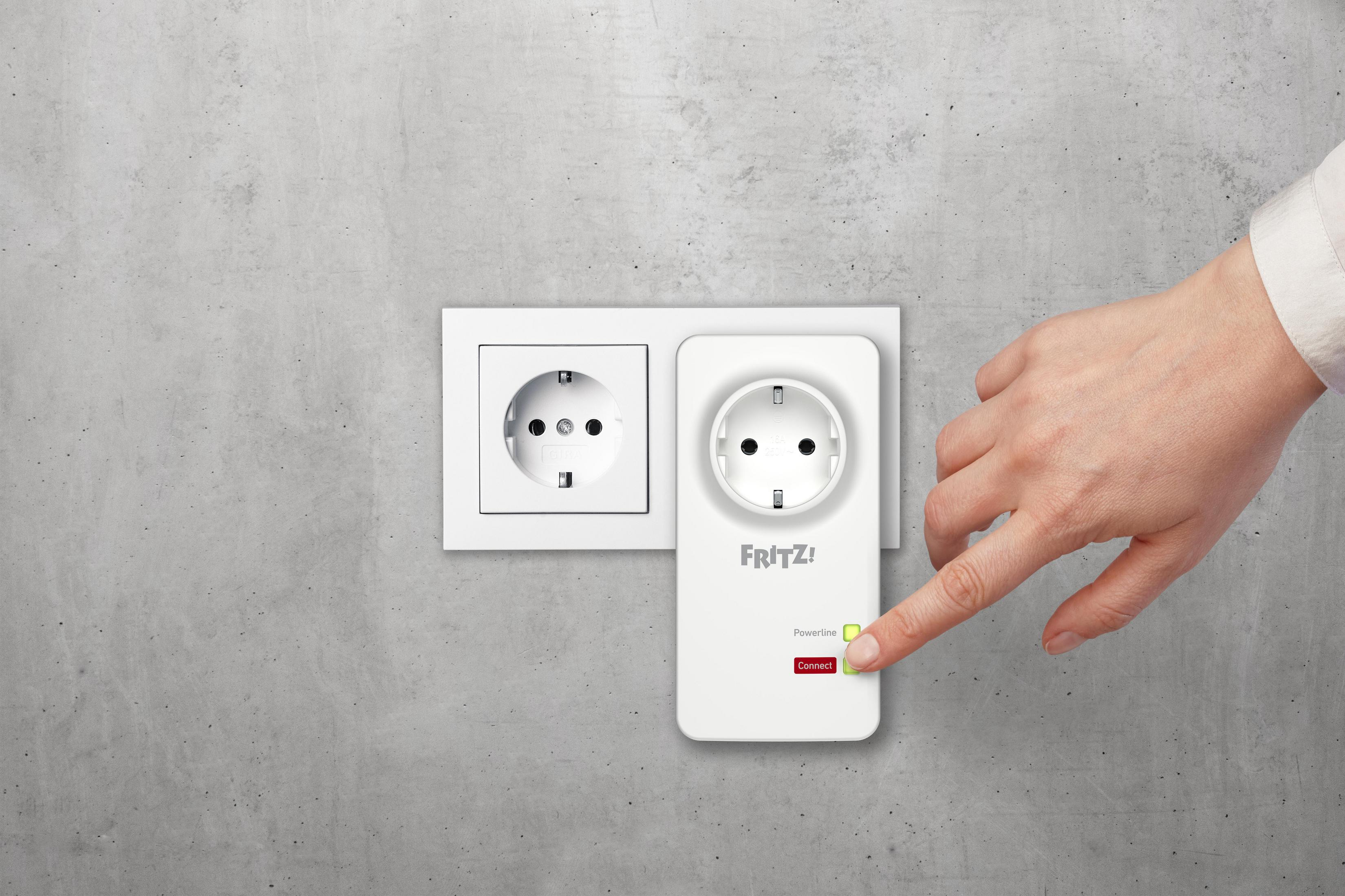 Biały adapter powerline w gniazdku. Ręka dotyka przycisku 'połącz', zielone światło.