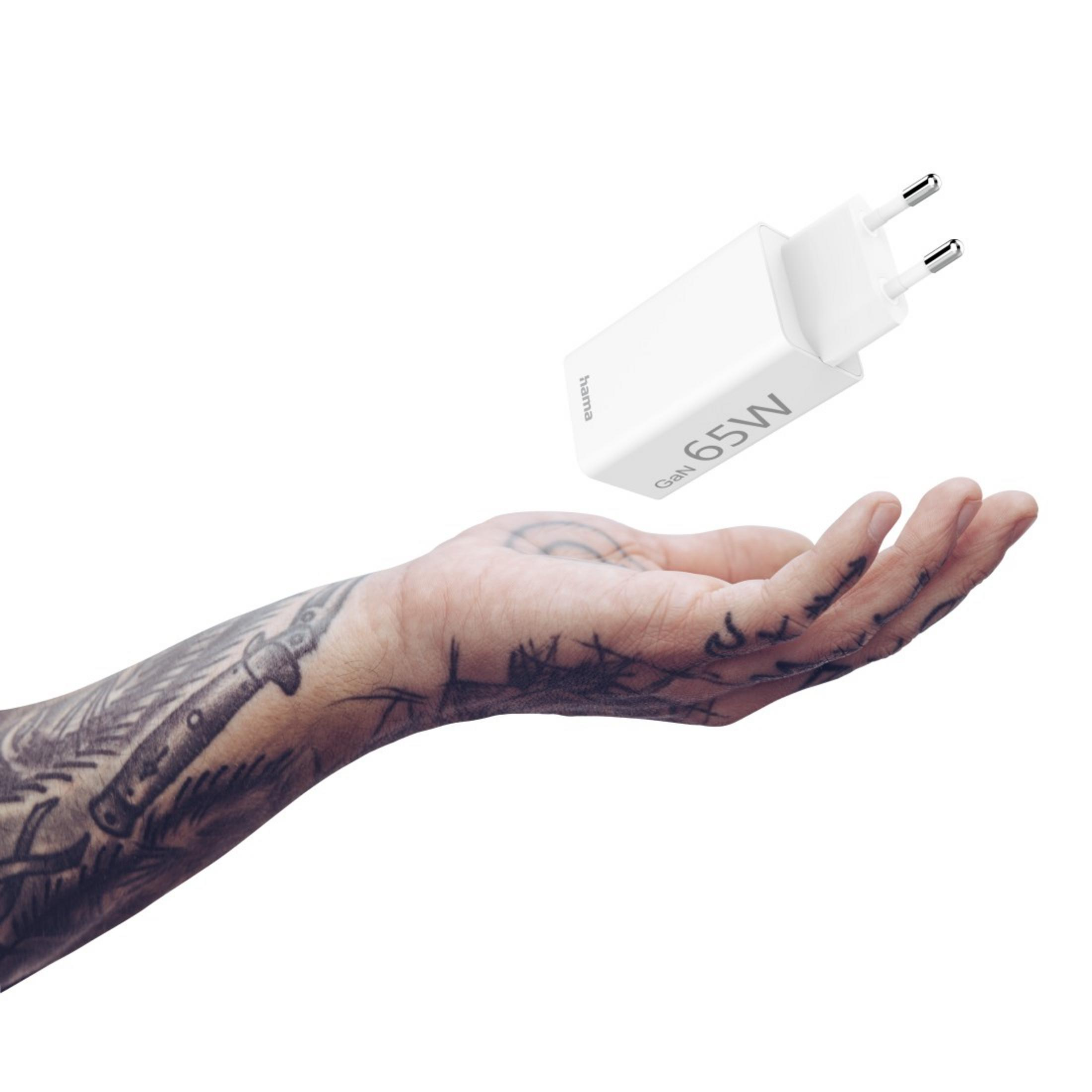 Ein weißes 65W-Ladegerät wird von einer Hand mit Tätowierung über weißem Hintergrund gehalten.