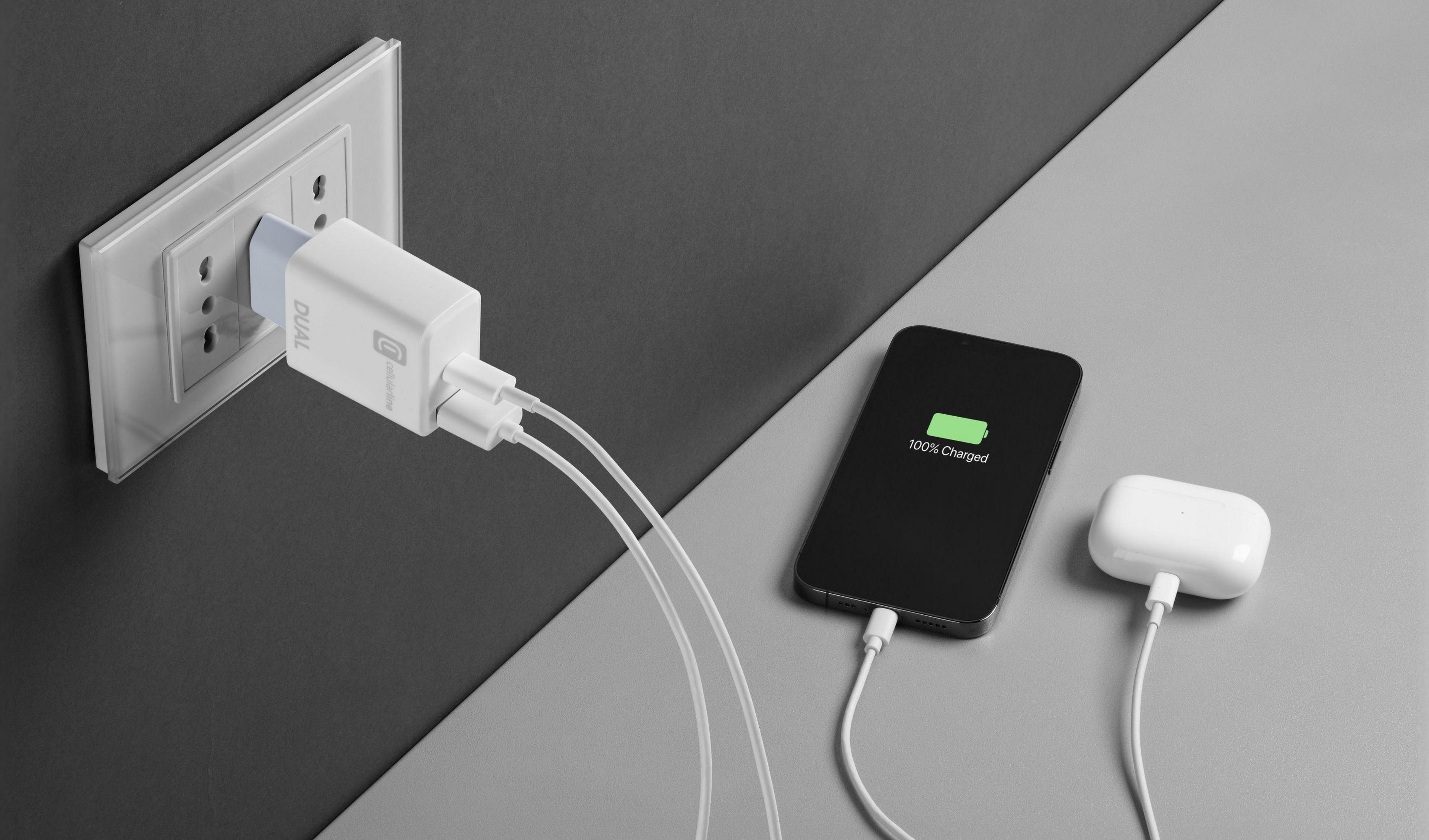 Phone and earbuds charging with a dual USB charger in outlet.