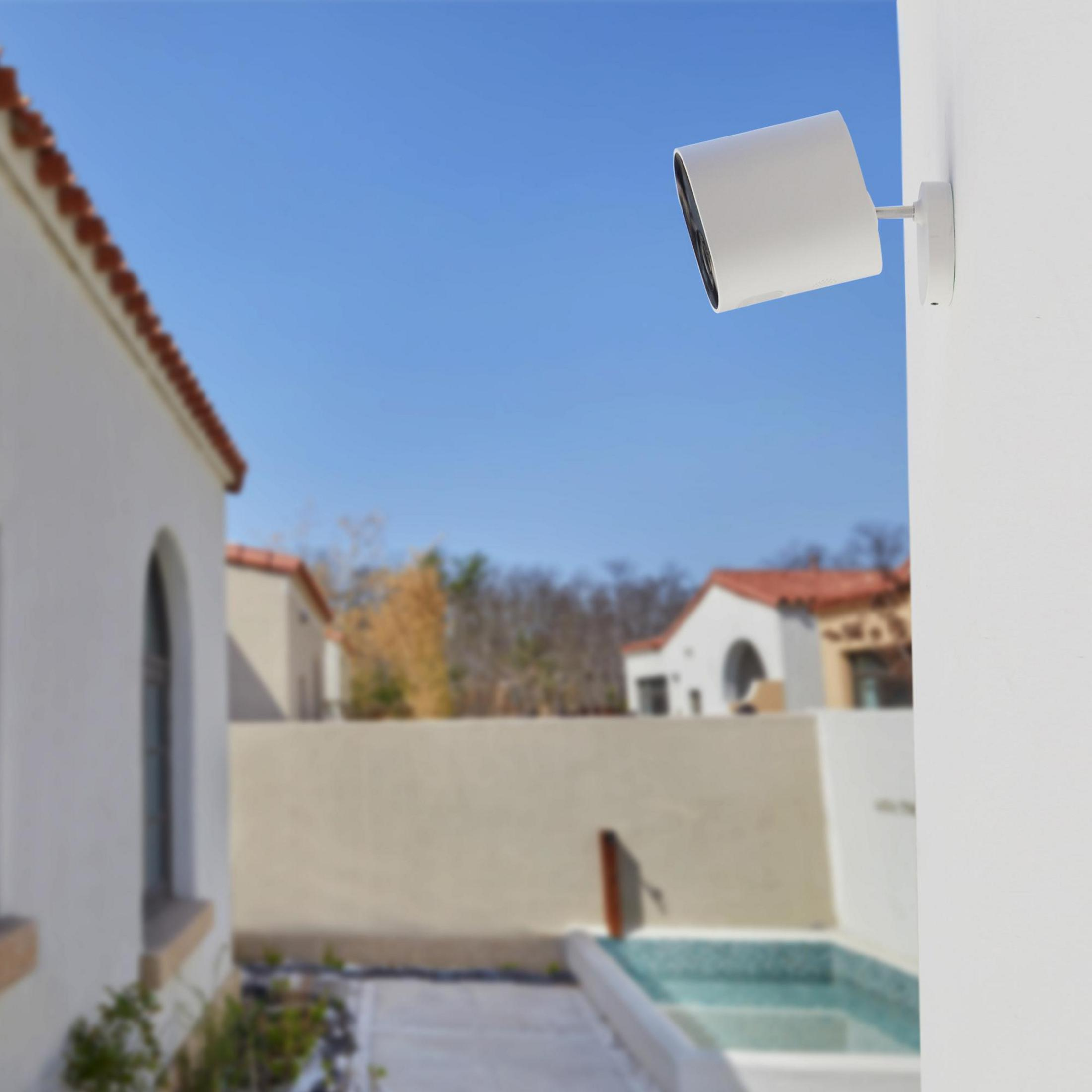 Telecamera di sicurezza bianca su un muro, con cielo blu sullo sfondo.