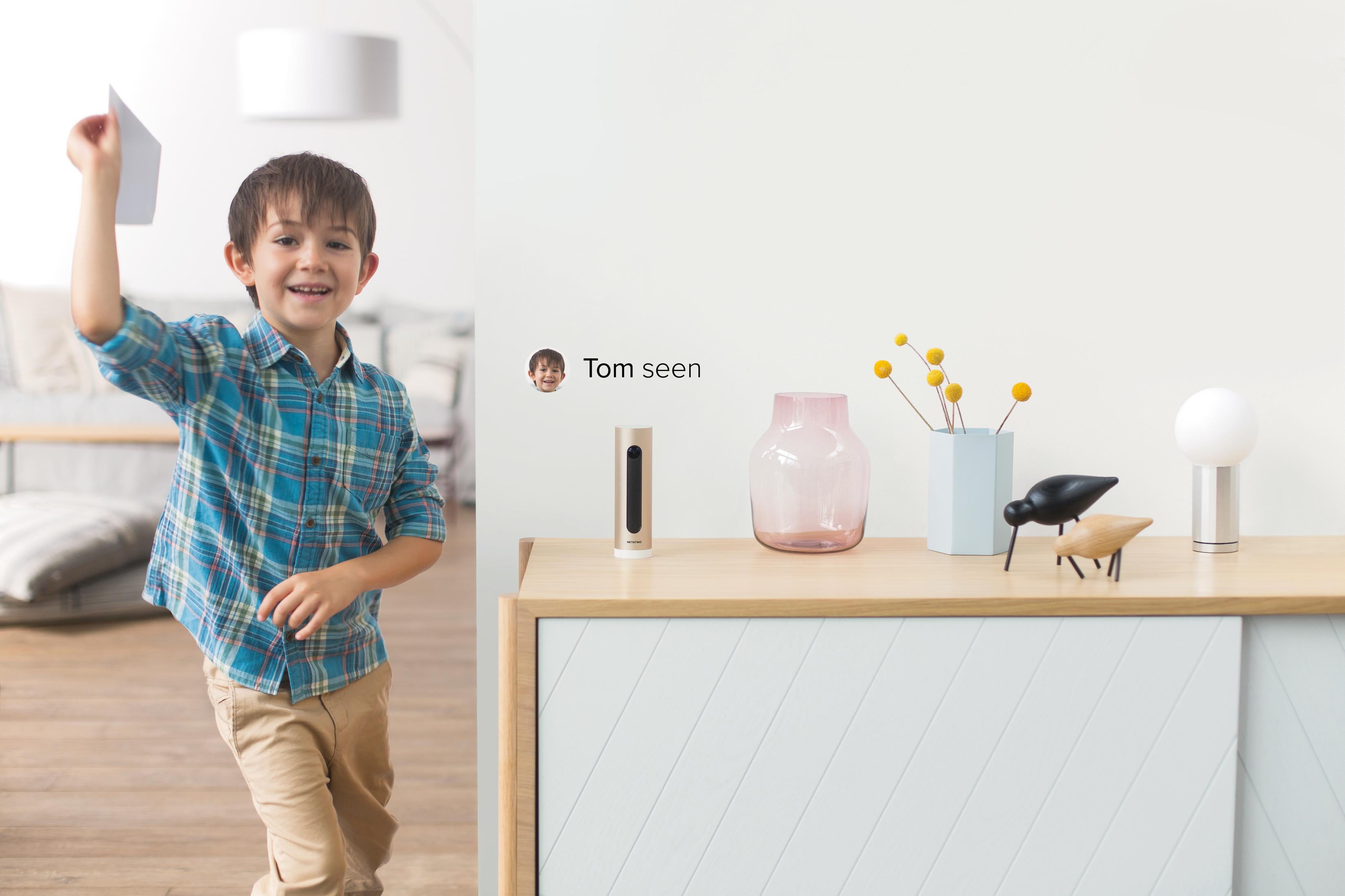 Chłopiec trzymający papier i uśmiechający się, z dekoracjami na stoliku.