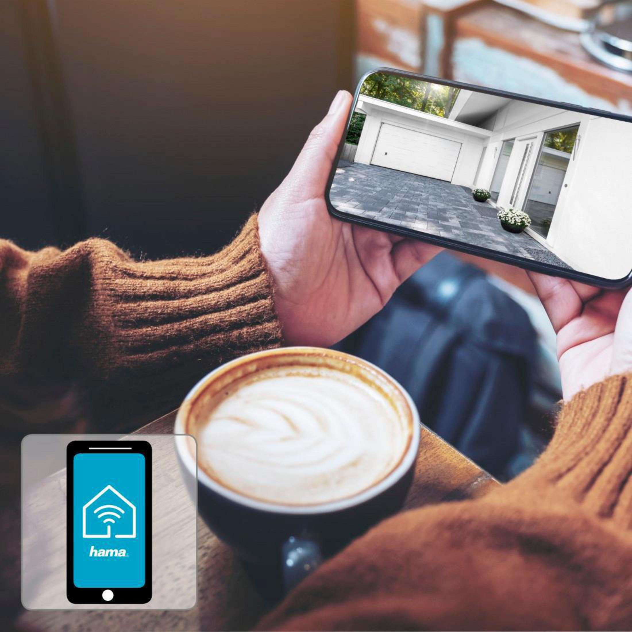 Eine Person hält ein Telefon, das eine Smart-Home-App mit einem Haussymbol zeigt.