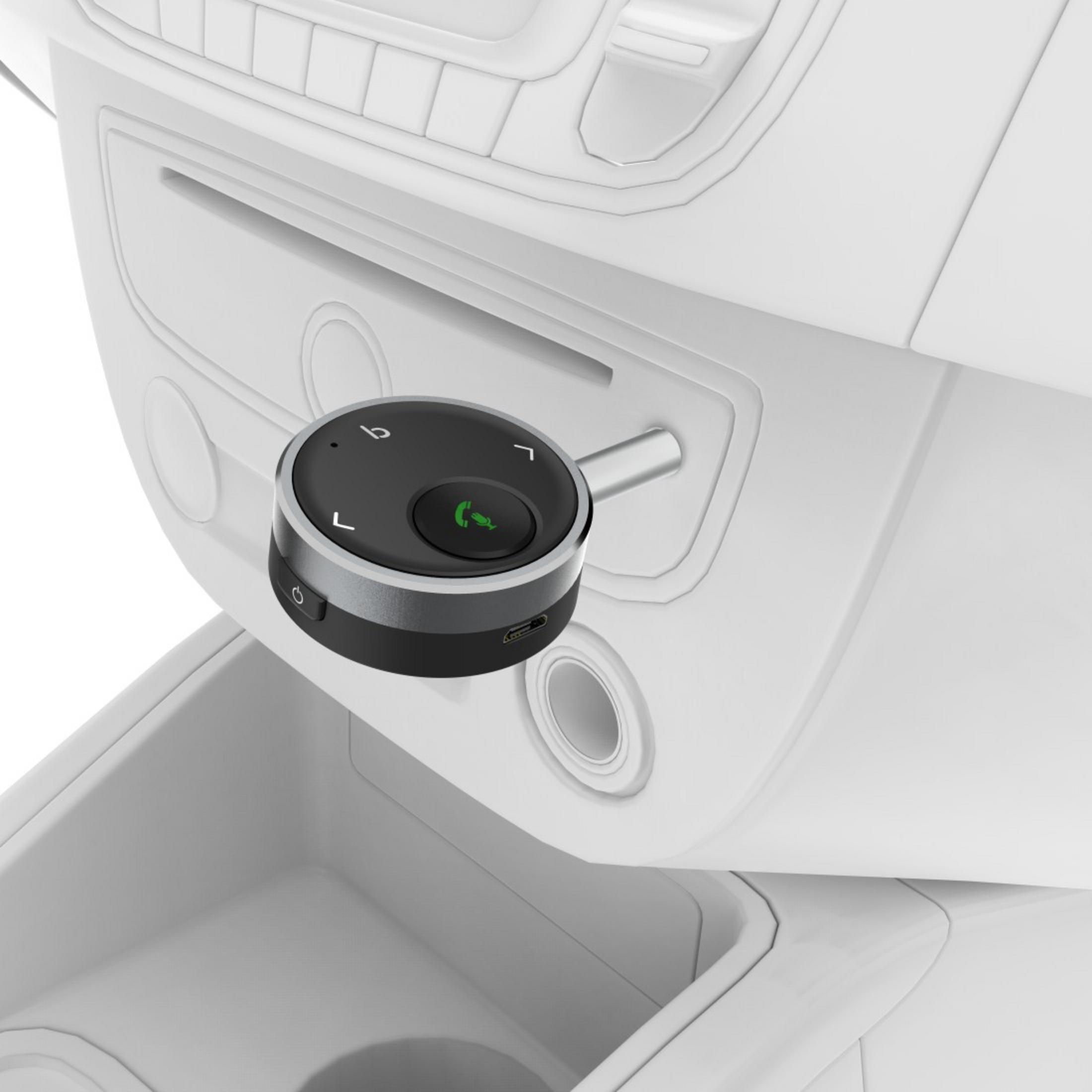 Wnętrze samochodu z deską rozdzielczą, panelem sterowania i okrągłym czarnym urządzeniem z zielonym przyciskiem połączenia.