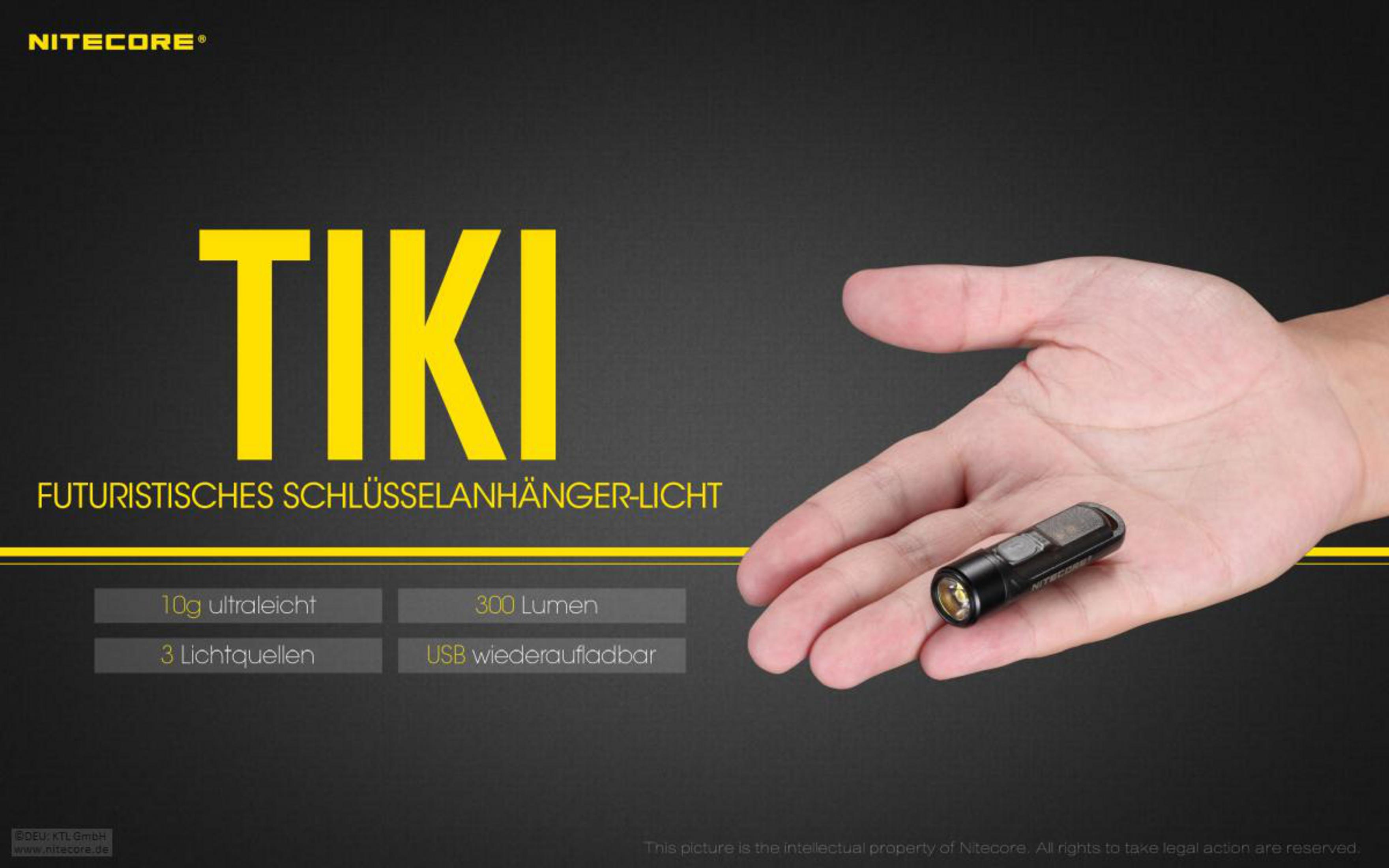 Eine Hand hält eine schwarze Nitecore TIKI Schlüsselanhänger-Taschenlampe vor einem schwarz-goldenen Hintergrund.