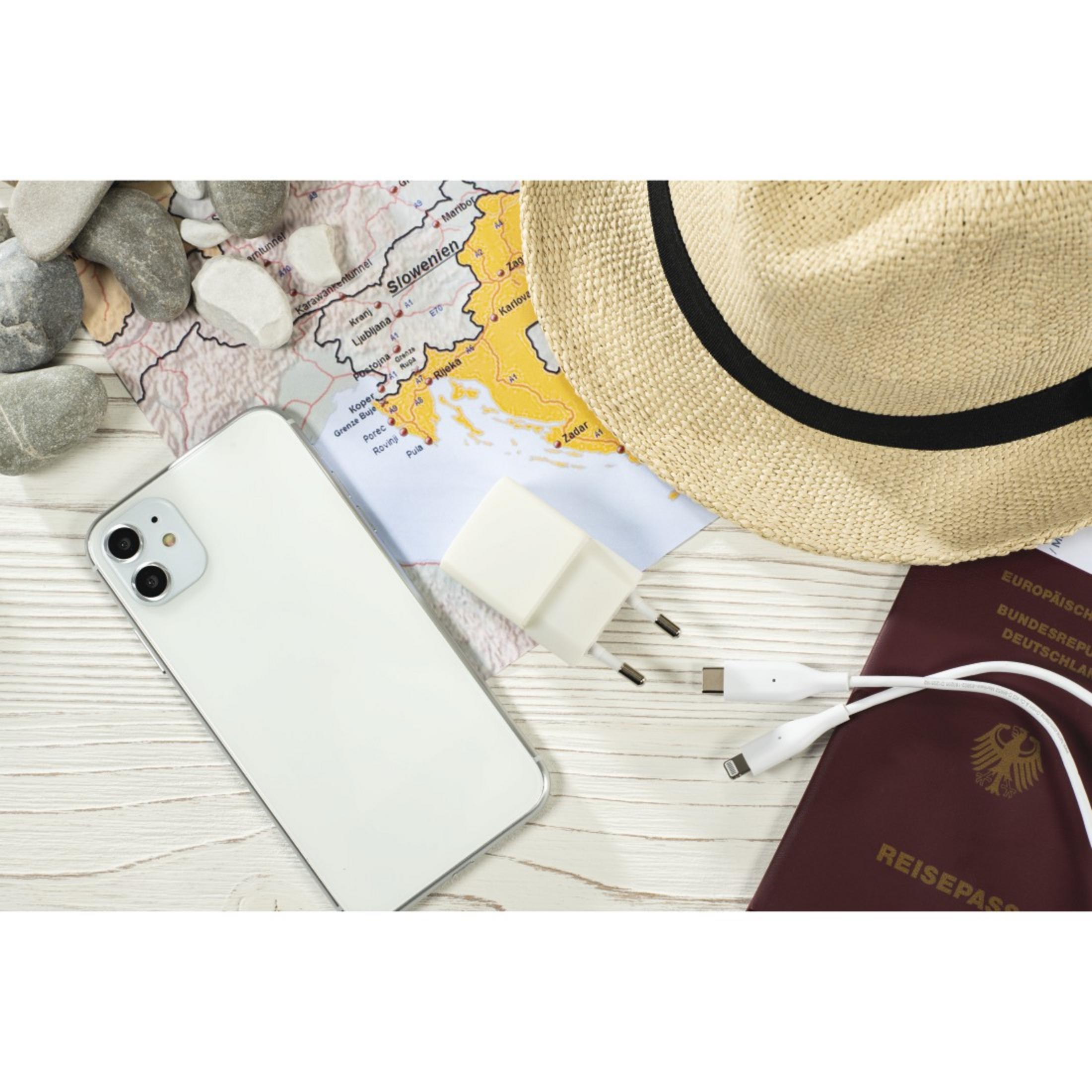 Telefon, ładowarka, kabel, paszport, mapa i kapelusz na drewnianej powierzchni.