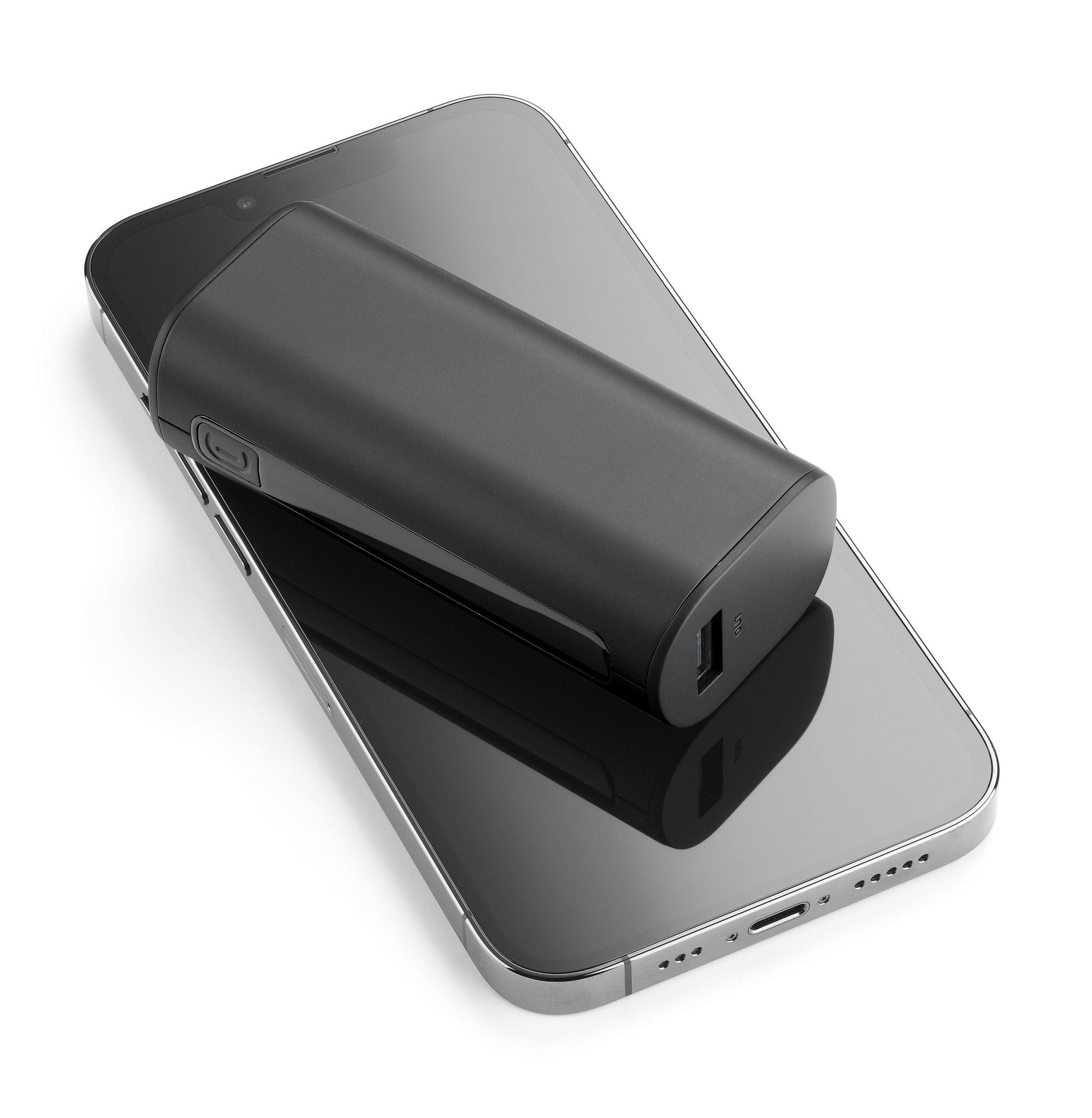 Schwarzes Telefon liegt auf einem Smartphone, mit einem schwarzen tragbaren Ladegerät oben drauf.