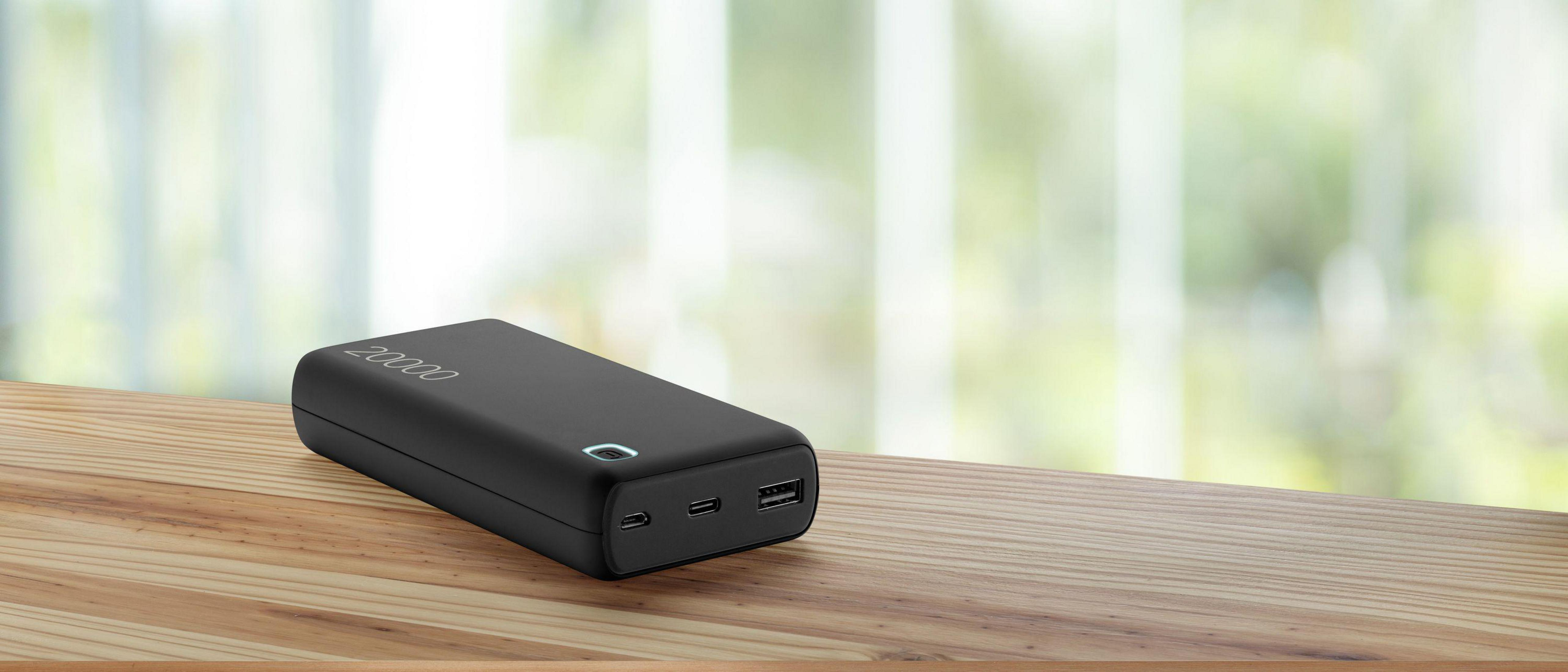 Power bank nero su un tavolo di legno, con il testo "20000" sulla sua superficie.