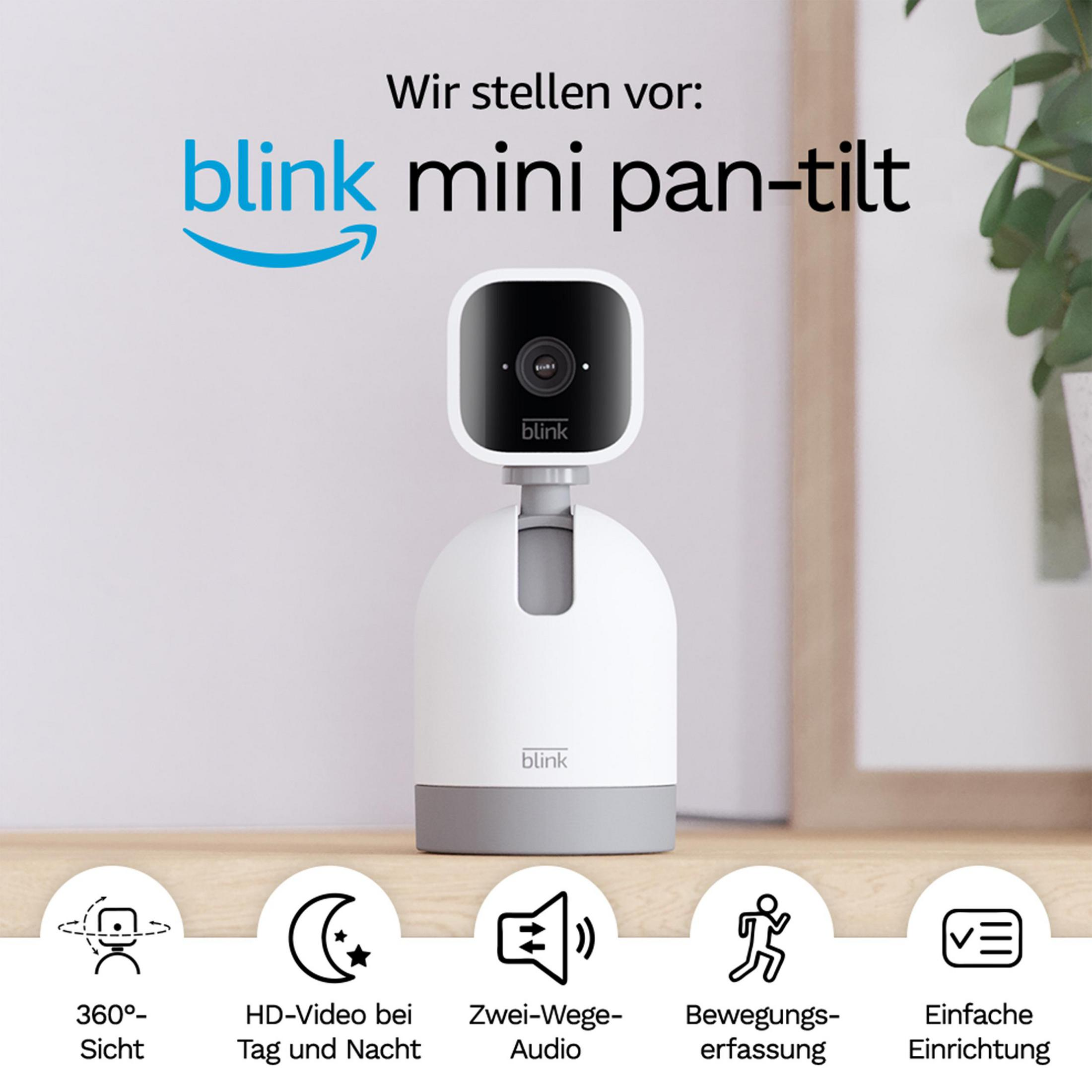 Kamera Blink Mini pan-tilt na stole. Biała podstawa, czarna kamera. Tekst i ikony widoczne na zdjęciu.