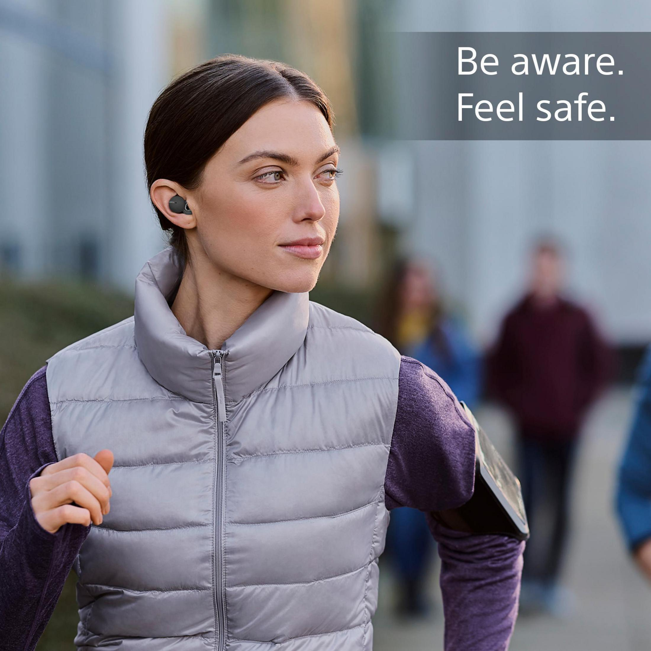 Kobieta biegnąca ze słuchawkami, w kamizelce i opasce na ramię. Tekst: Bądź świadomy. Poczuj się bezpiecznie.