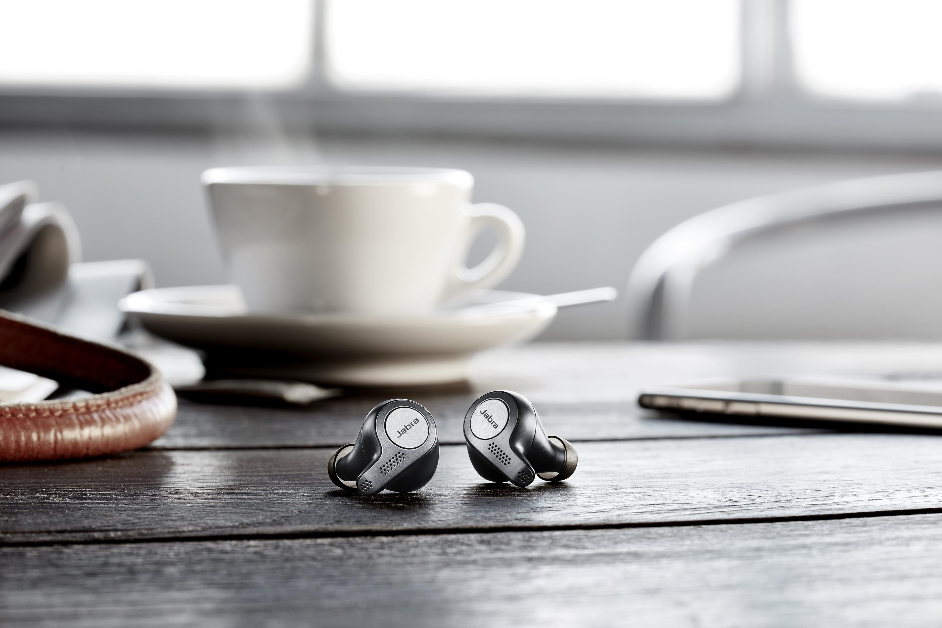 Auricolari su un tavolo di legno con una tazza di caffè e un giornale. Il fumo si alza.