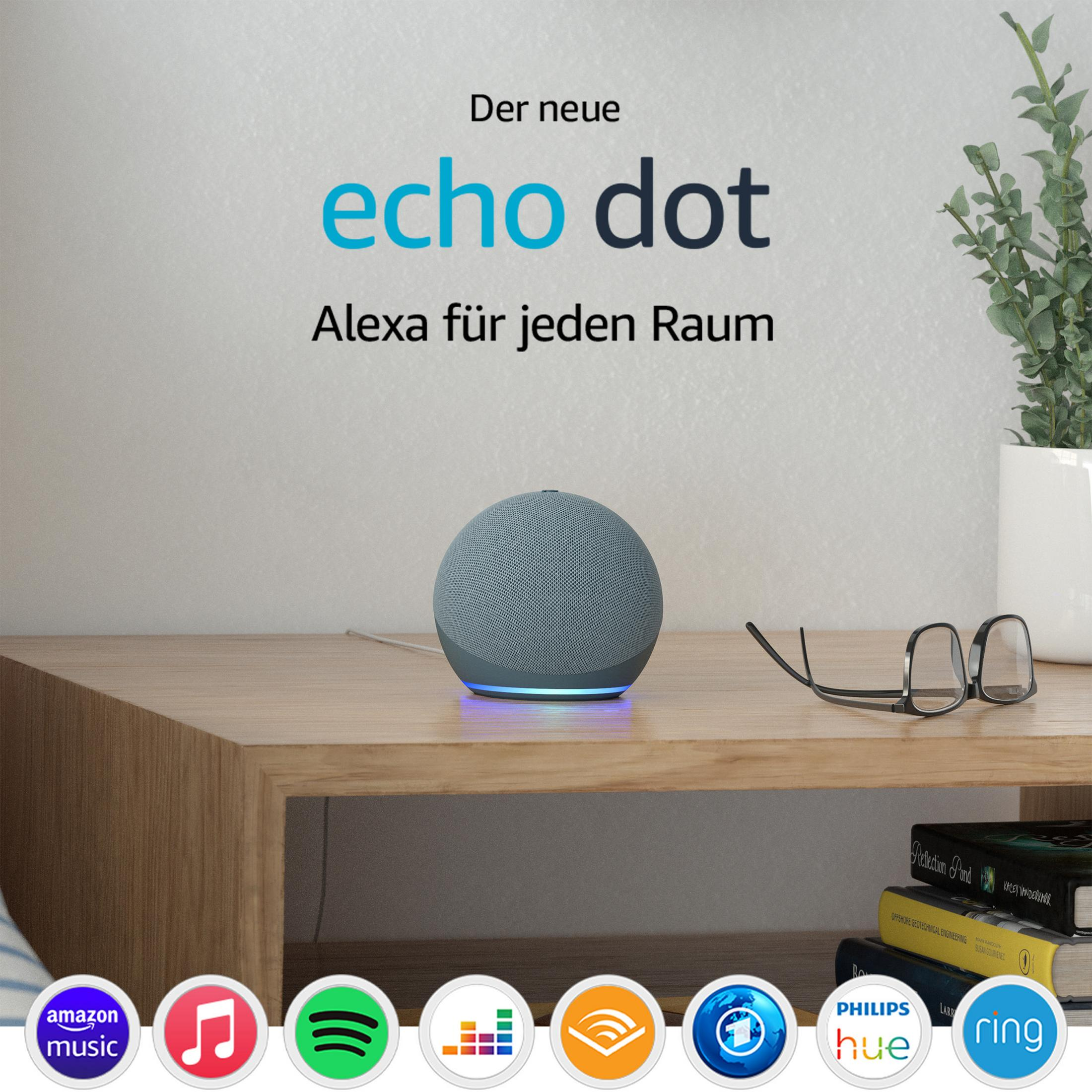 Grauer Echo Dot auf Holztisch. Text: Der neue Echo Dot, Alexa für jeden Raum. Im Hintergrund Grünpflanze.