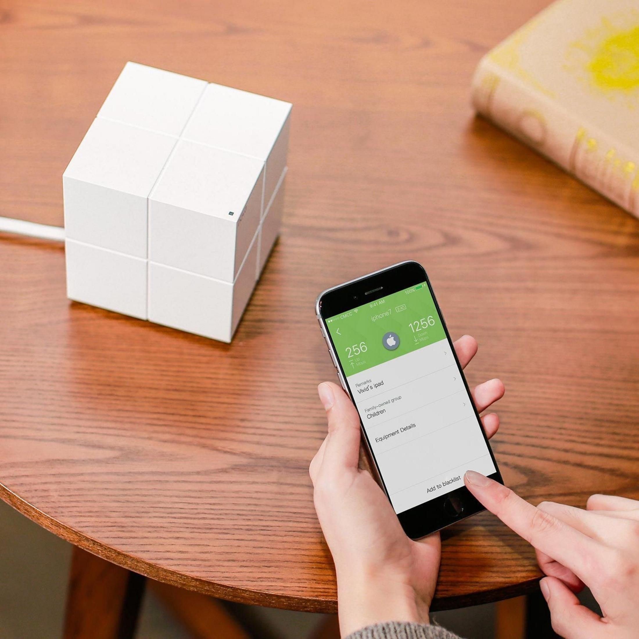 Białe urządzenie w kształcie kostki obok smartfona z interfejsem smart home.