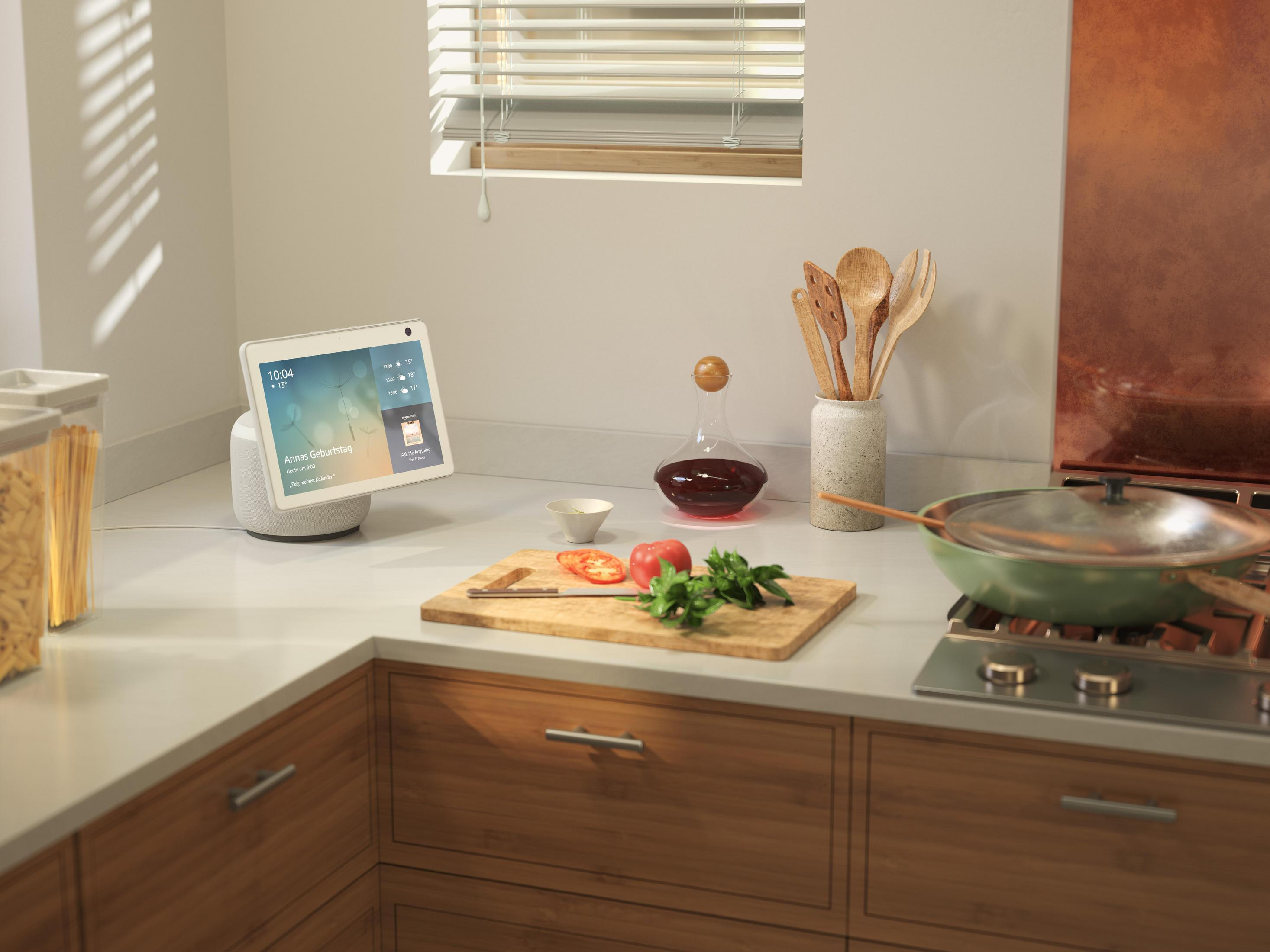 Küchentheke mit Smart-Display, Schneidebrett und Küchenutensilien.