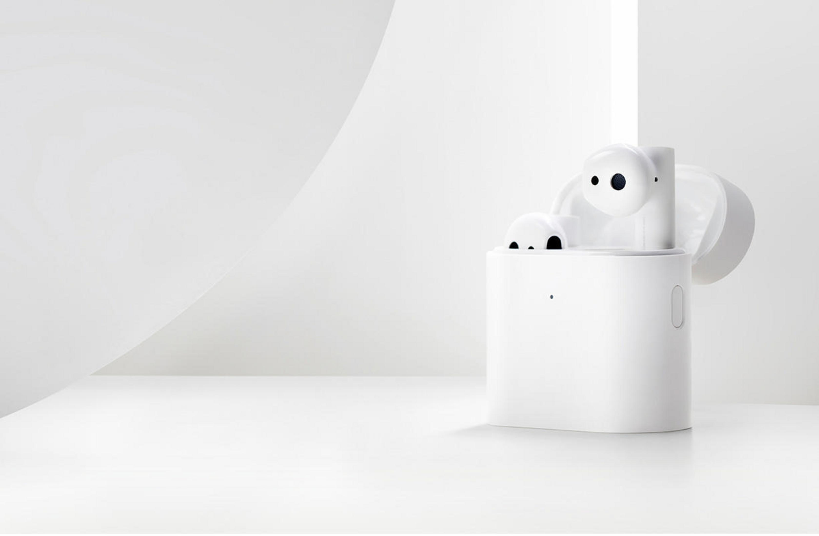 Białe bezprzewodowe słuchawki douszne w etui ładującym. Etui jest otwarte, słuchawki widoczne.