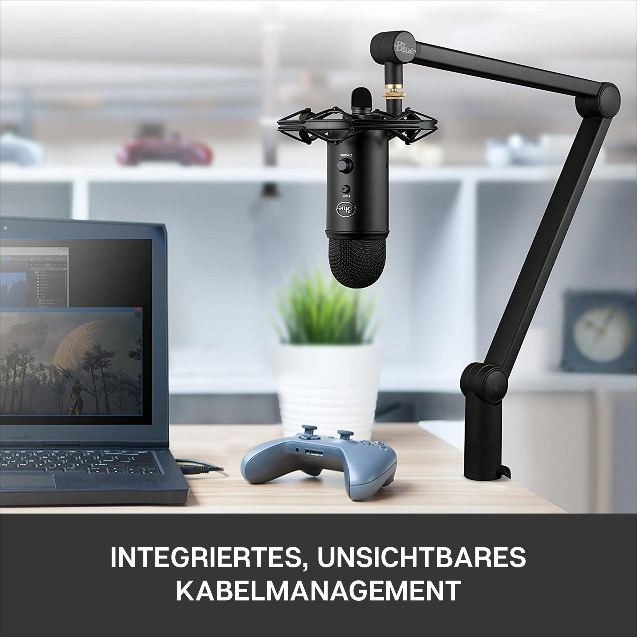 Schwarzes Mikrofon mit Controller und Laptop auf einem Schreibtisch.