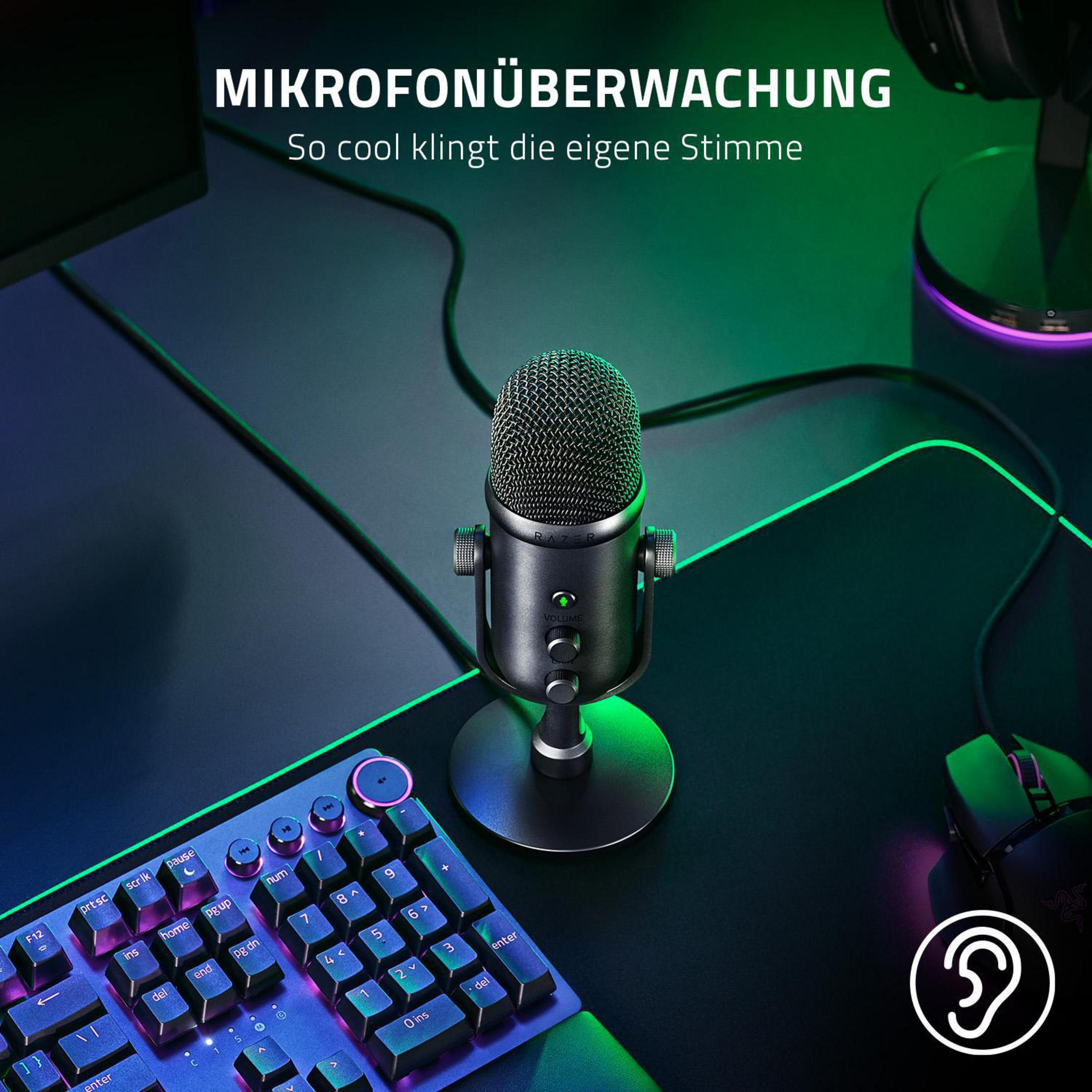 Zwarte Razer microfoon op een standaard, met een toetsenbord, muis en monitor op de achtergrond.