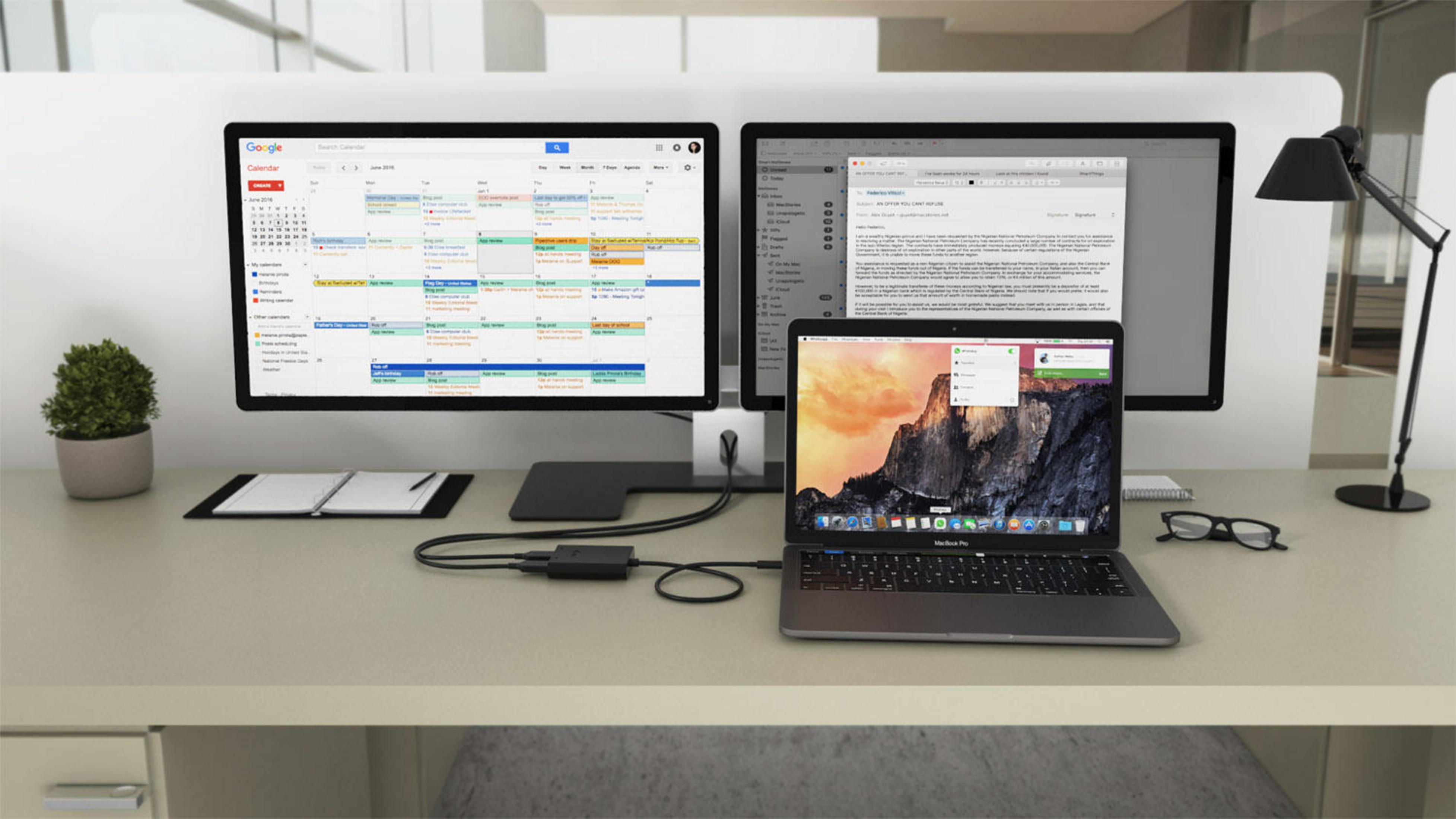 Scrivania con due monitor, un laptop e attrezzature per ufficio. Scena con luce intensa.