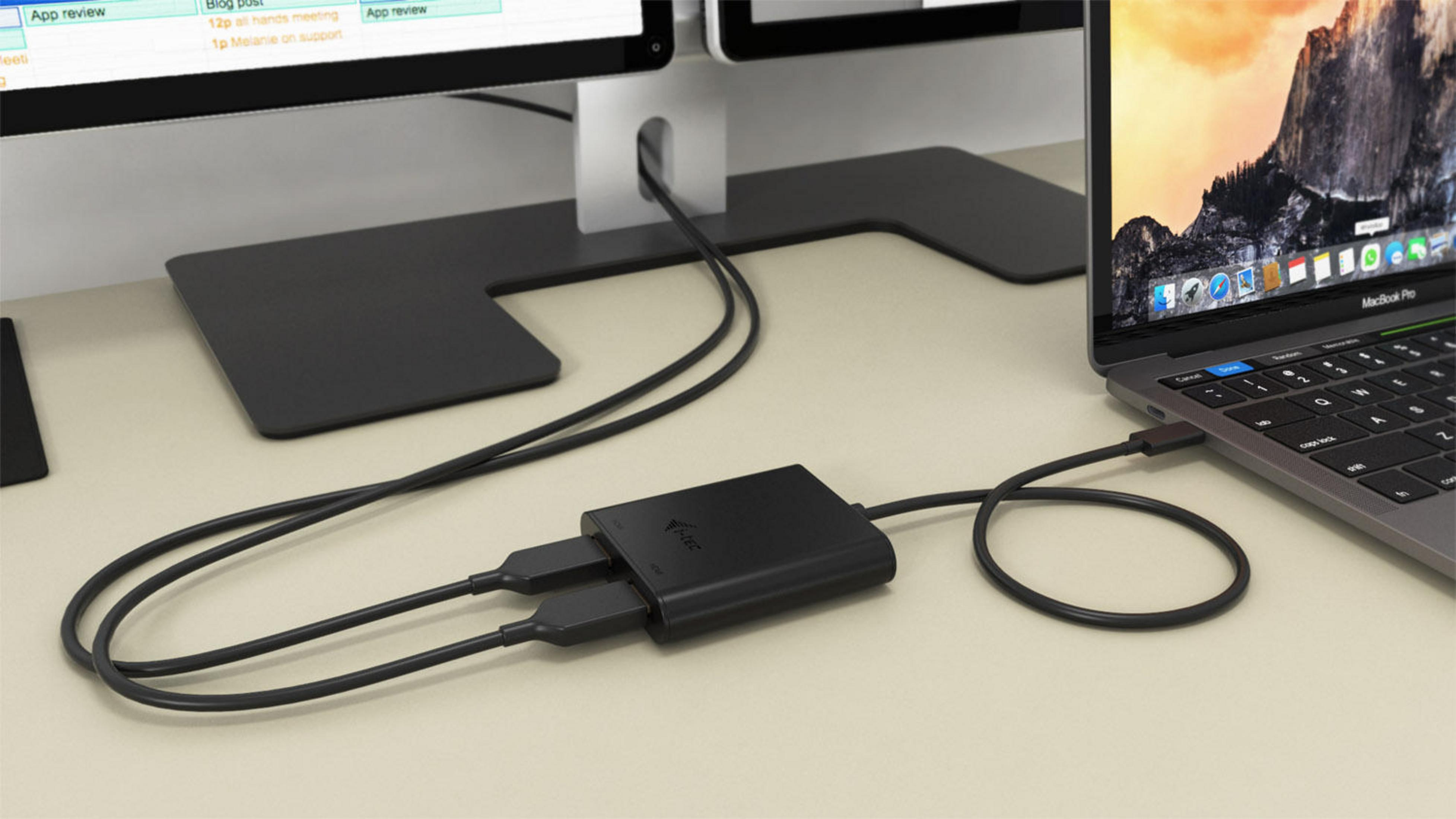 Hub nero collegato a laptop e monitor, su una scrivania, con cavi.