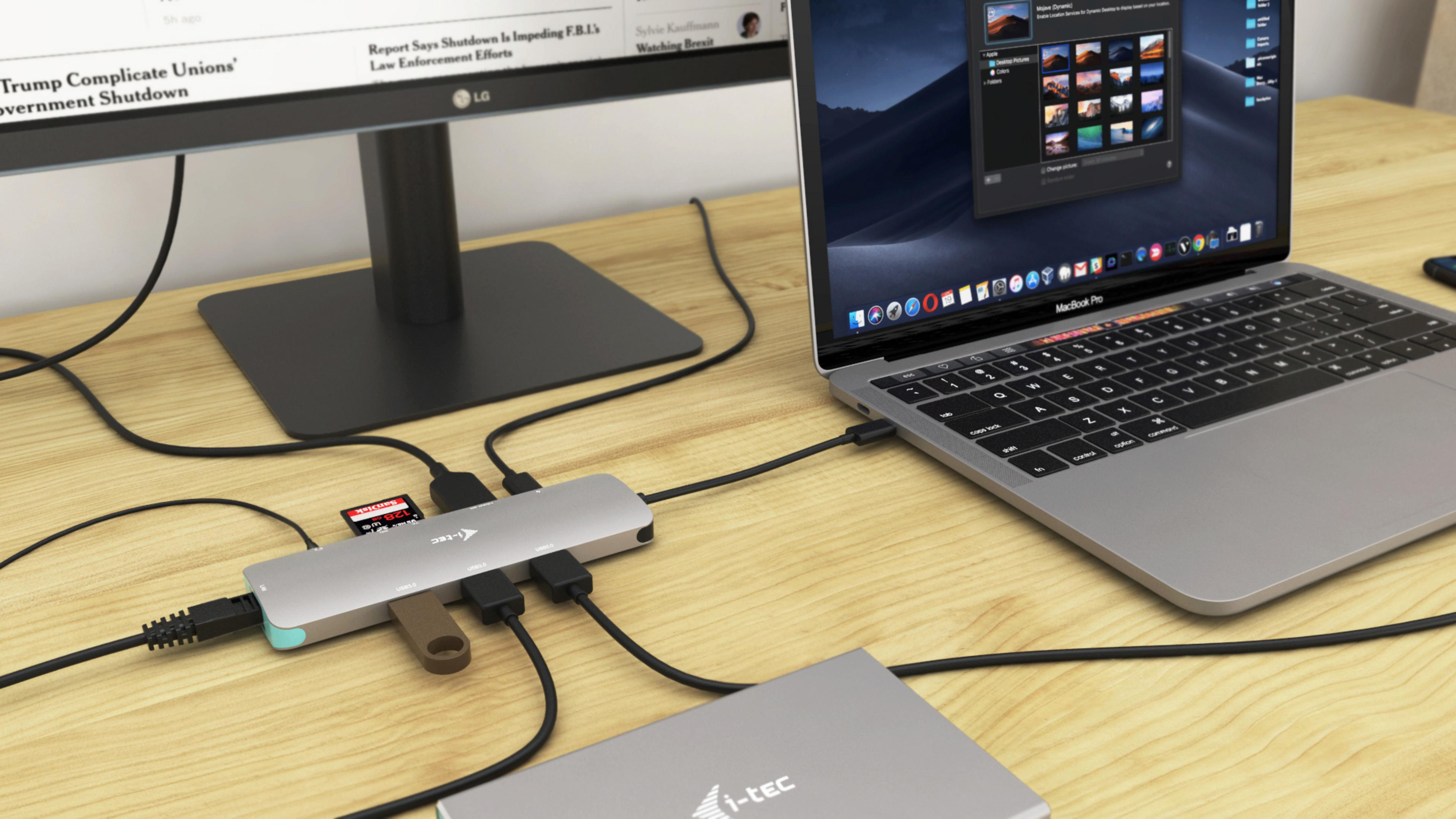 Ein Laptop ist mit einem Hub mit mehreren Steckern verbunden. Ein Monitor ist ebenfalls angeschlossen.