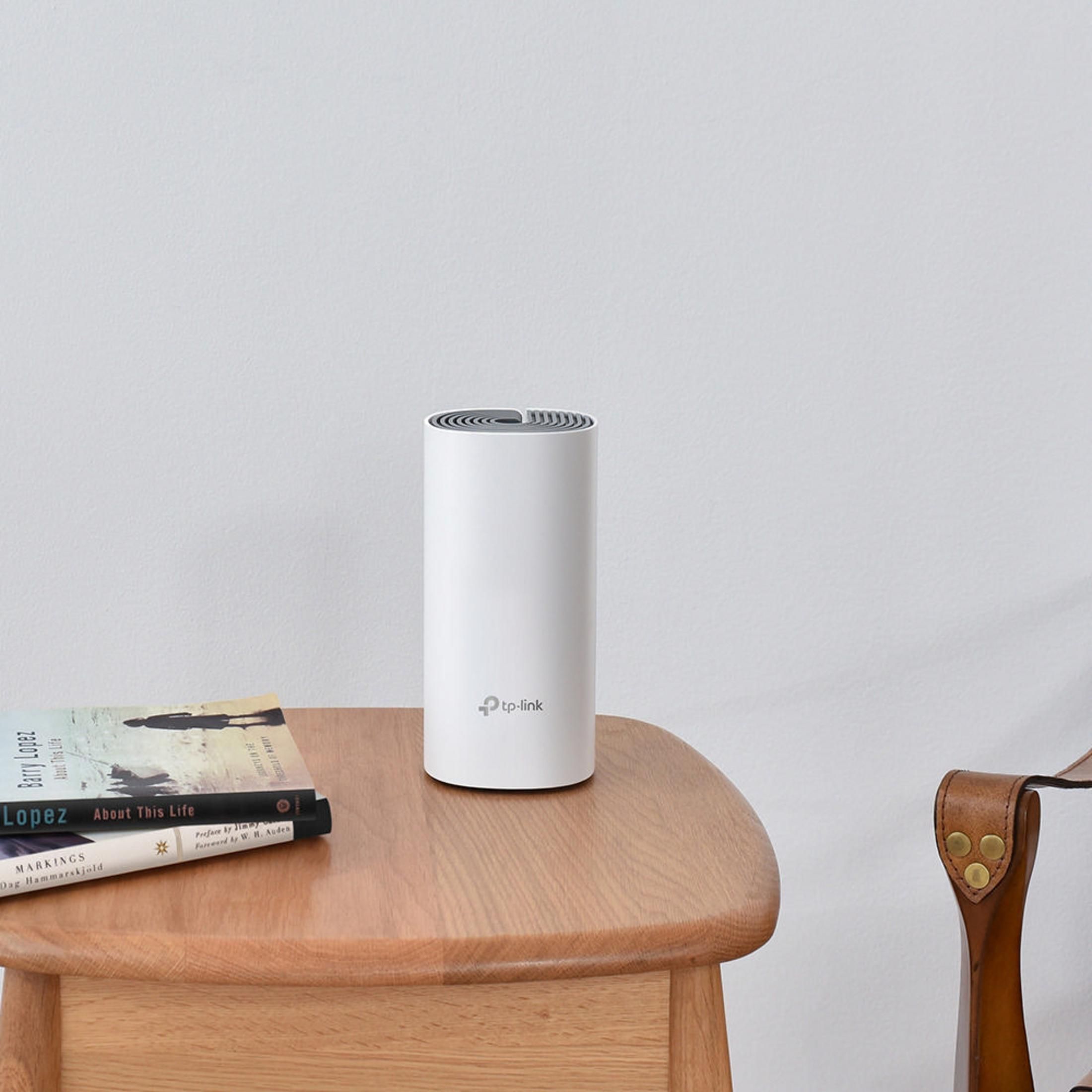 Een witte TP-Link cilindrische router op een houten tafel. Boeken in de buurt. Witte muur op de achtergrond.