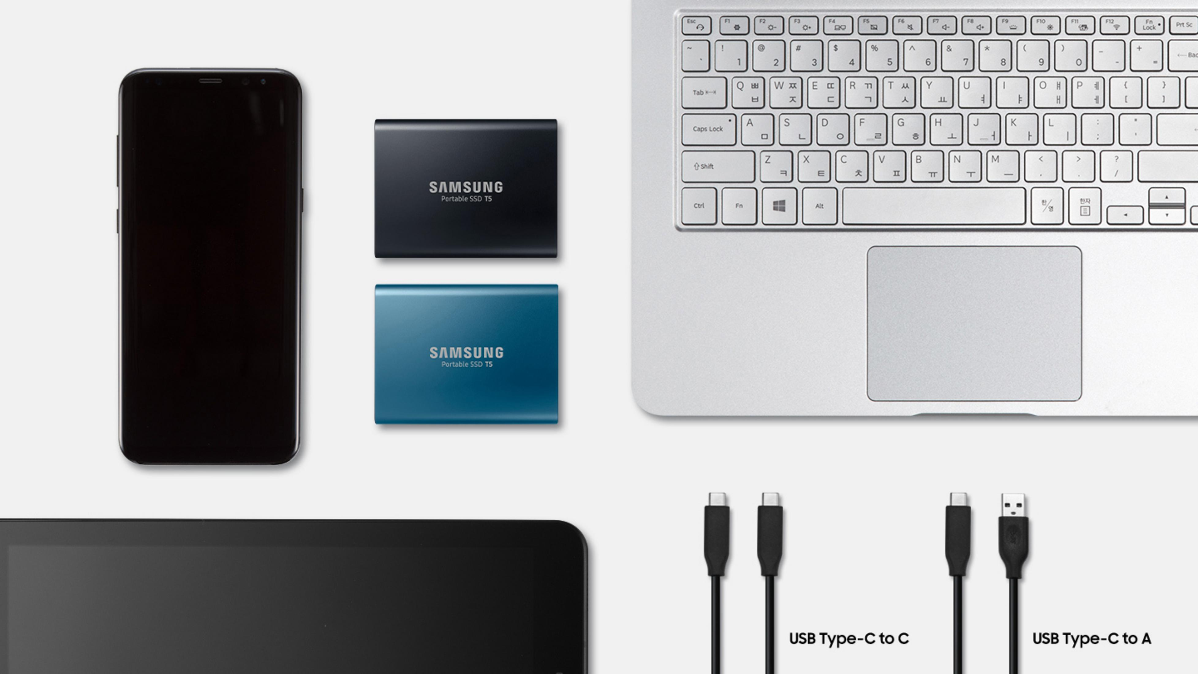 Un telefono, due SSD, un tablet, un laptop e vari cavi sono disposti su uno sfondo chiaro.