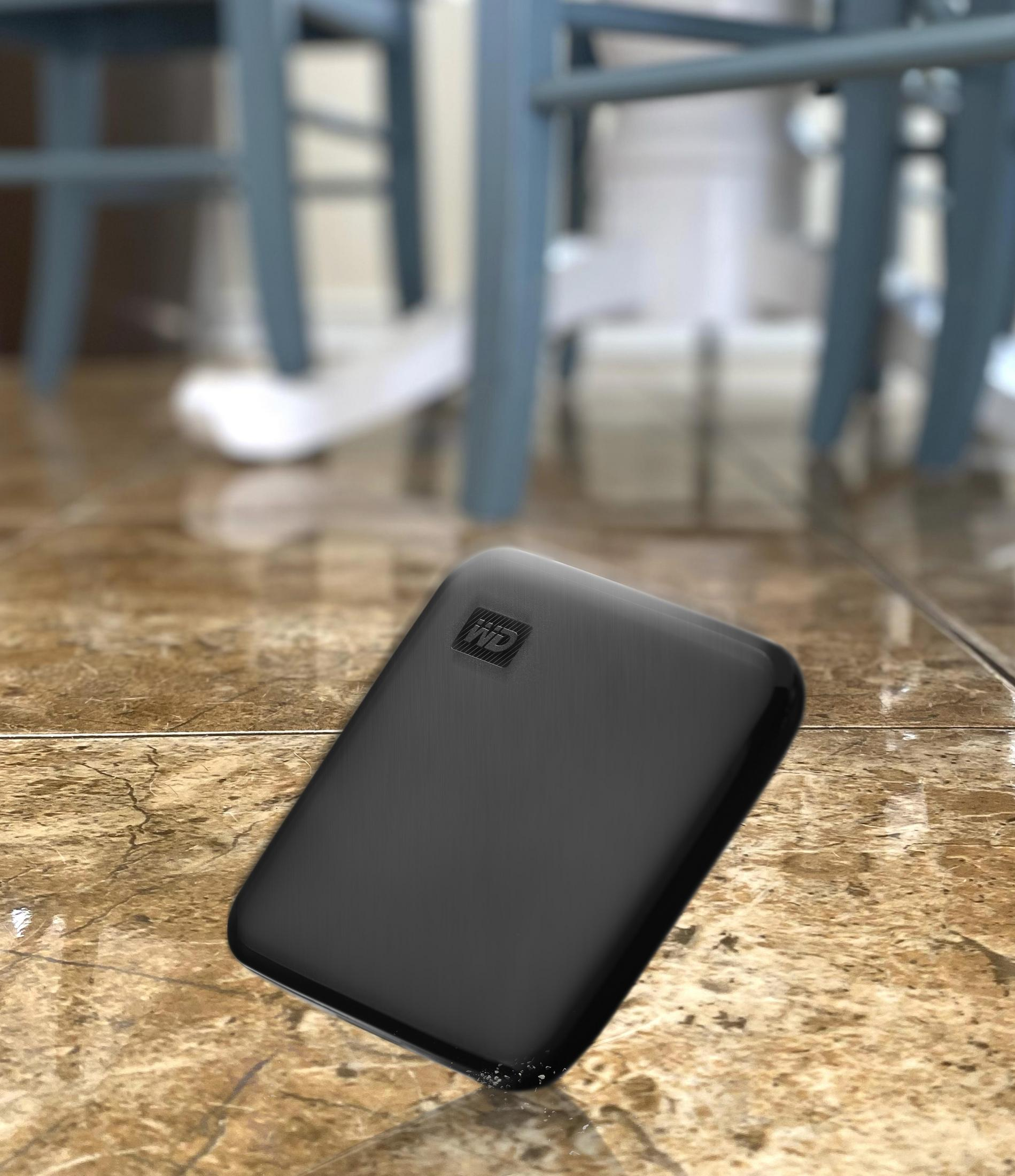 Czarny przenośny dysk twardy na wzorzystej powierzchni, rozmyte tło.